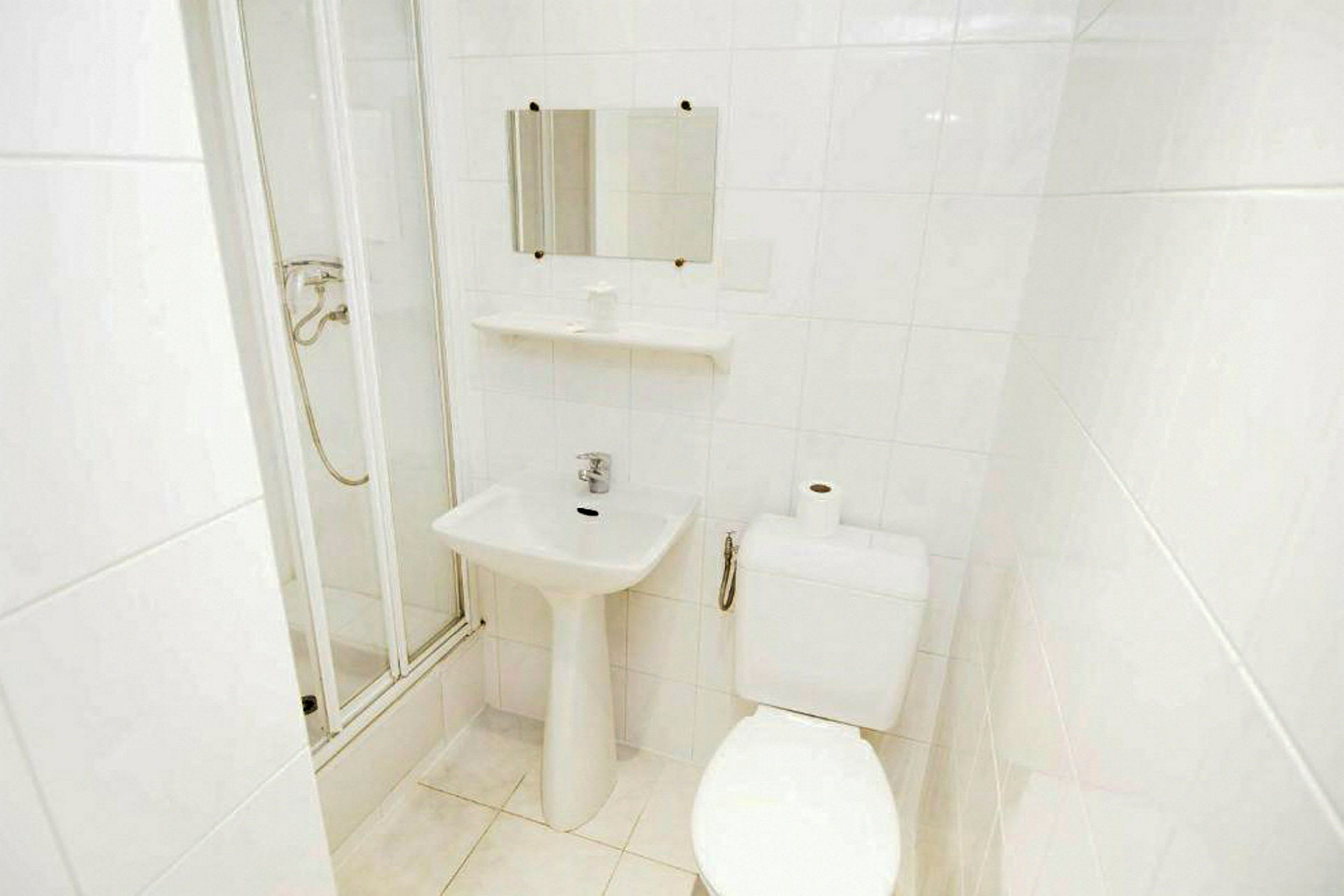 Badeværelse med toilet, håndvask og brusekabine. (AI-genereret tekst)