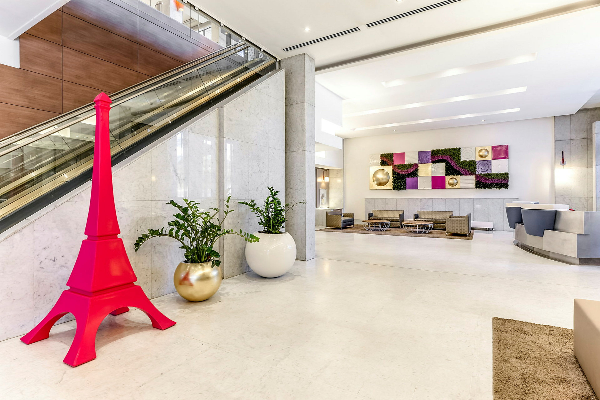 Hotellobby med moderne indretning, inklusive en pink dekoration formet som et tårn. (AI-genereret tekst)