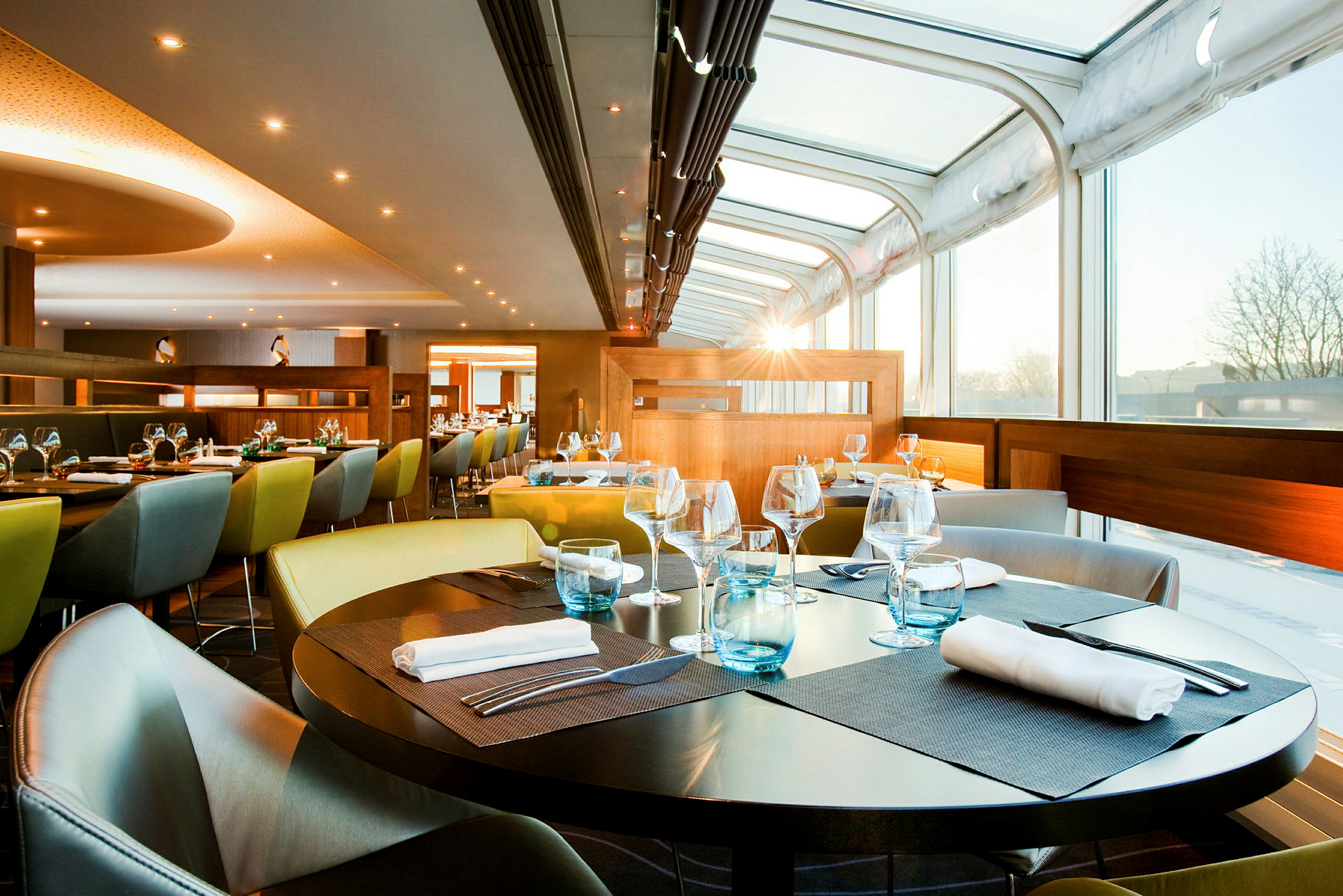 En moderne restaurant med glasvægge og opdækkede borde med servietter og glas. (AI-genereret tekst)