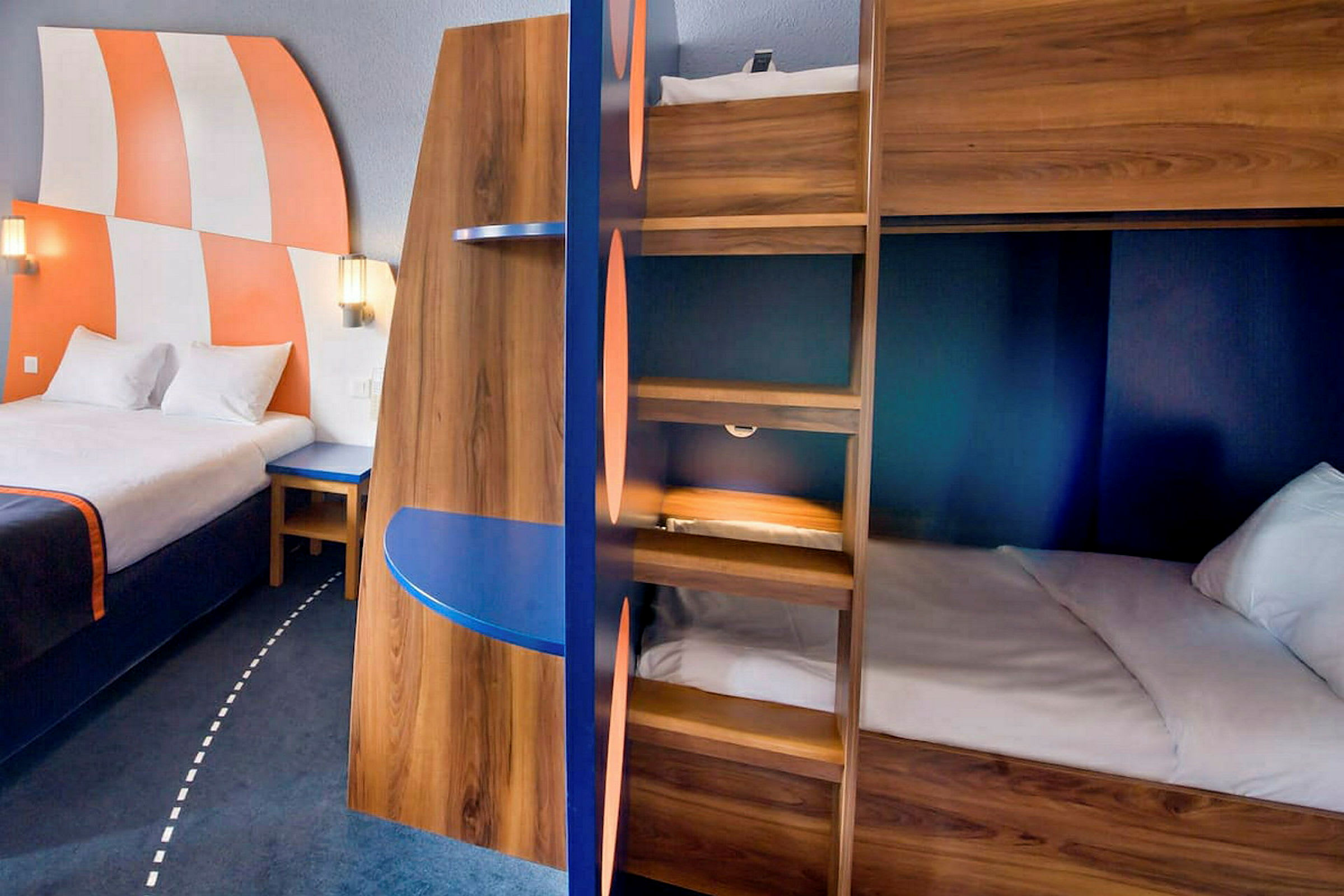 Interiør af et hotelværelse med en stor seng, køjesenge og farverige detaljer. (AI-genereret tekst)