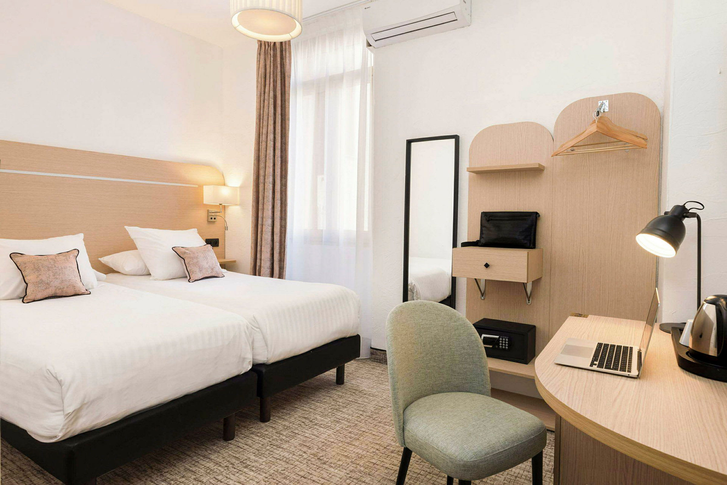 Hotelværelse med to enkeltsenge, et skrivebord, stol og garderobe. (AI-genereret tekst)