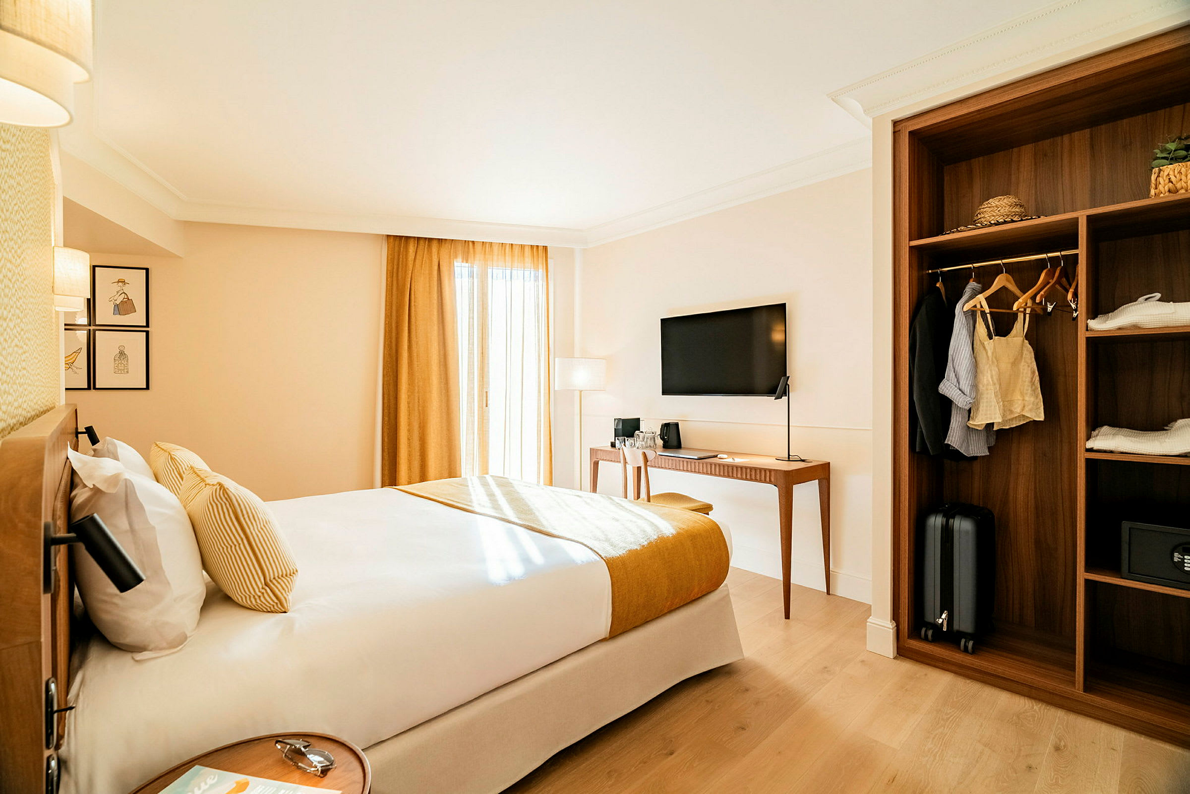 Et hotelværelse med en dobbeltseng, et tv på væggen, et skrivebord og en garderobe med tøj og bagage. (AI-genereret tekst)