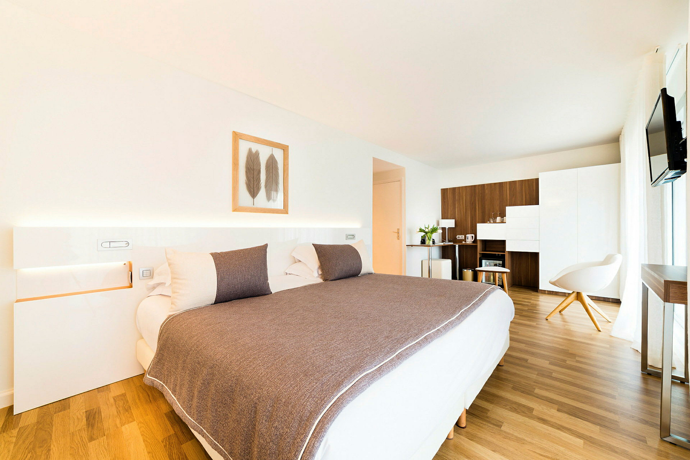 Et moderne hotelværelse med en stor seng, minimalistisk indretning og trægulv. (AI-genereret tekst)