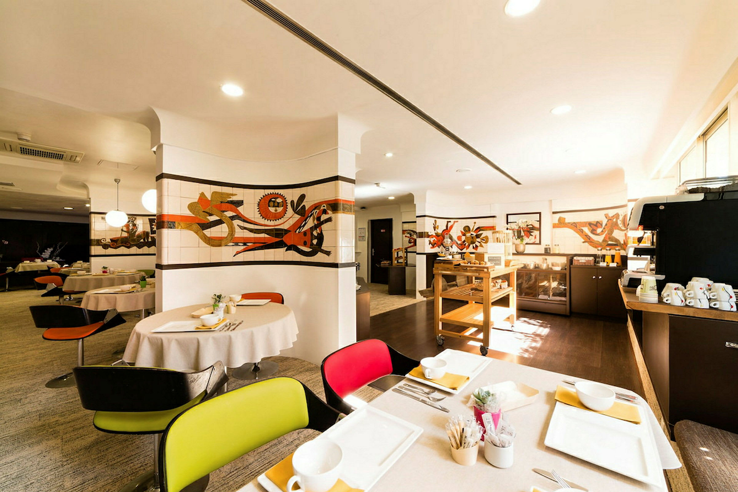 En restaurant med dækkede borde, kunst på væggene og en serveringsstation. Lyset er varmt og indbydende. (AI-genereret tekst)