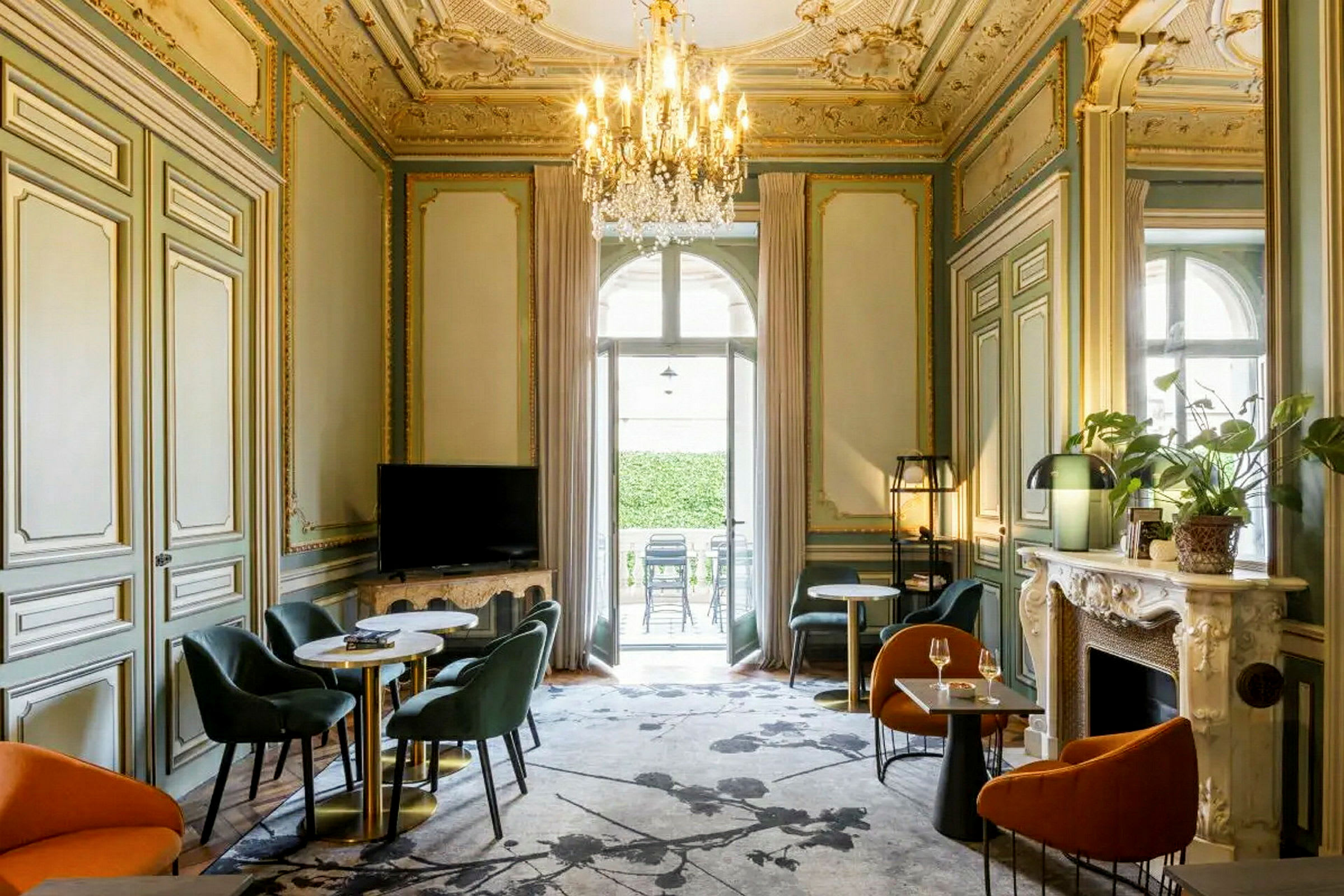 Et elegant møbleret rum med udsmykket loft, siddegrupper og en lysekrone. (AI-genereret tekst)