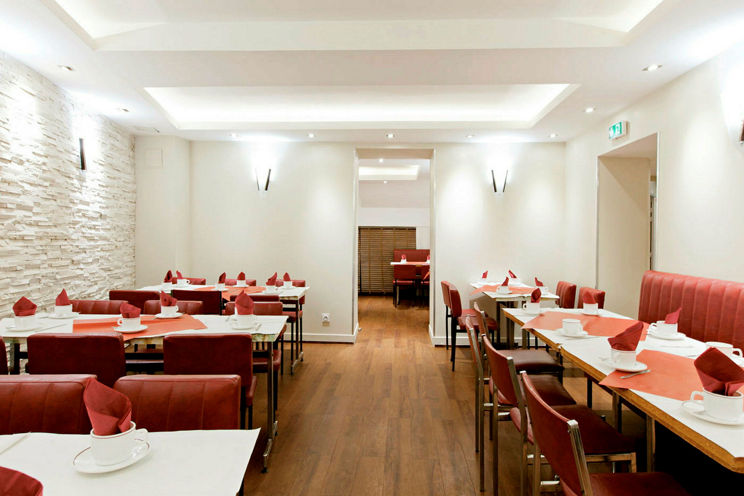 Restaurant med dækkede borde og røde stole. (AI-genereret tekst)