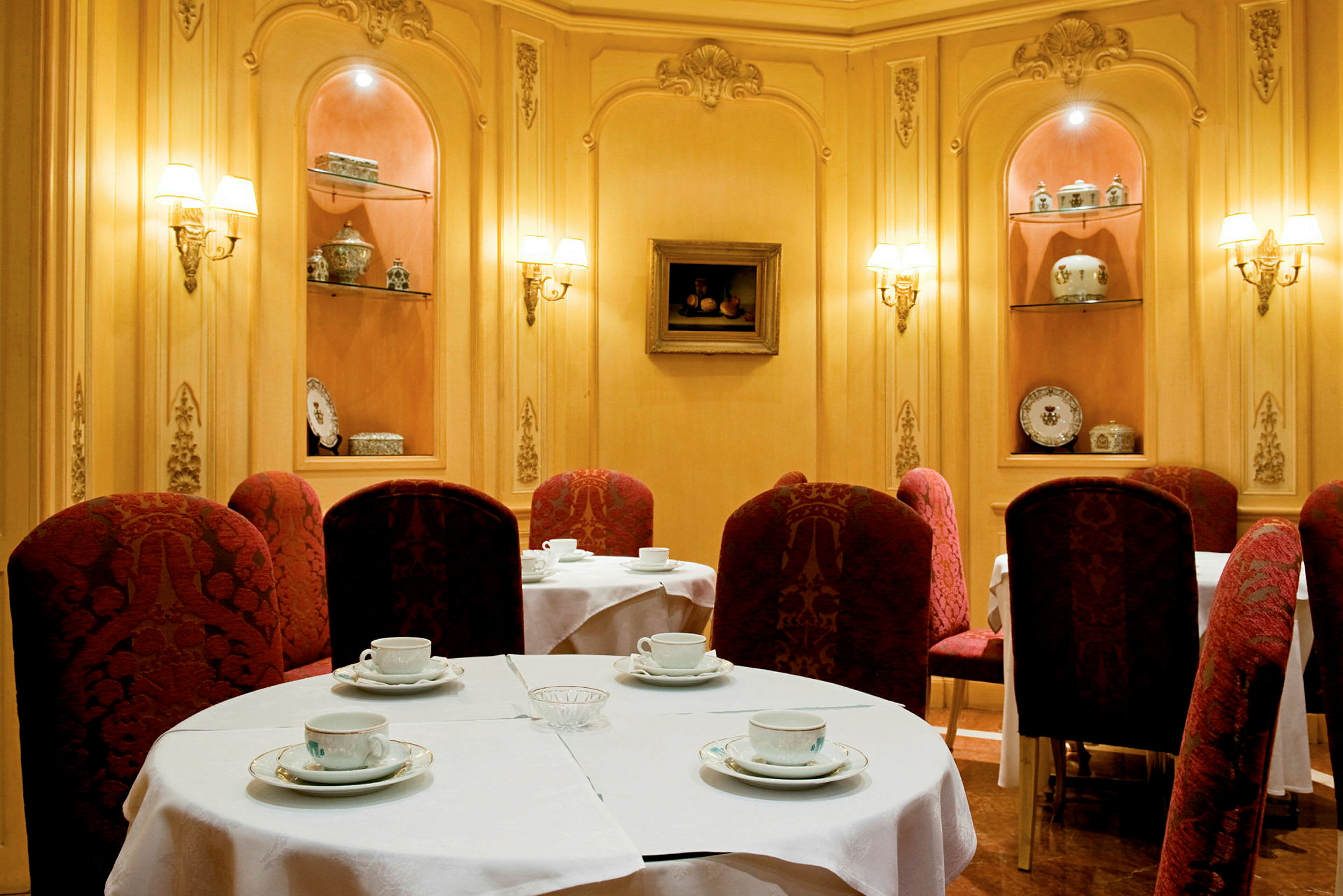 En elegant indrettet café med borde dækket med hvide duge og røde stole. (AI-genereret tekst)
