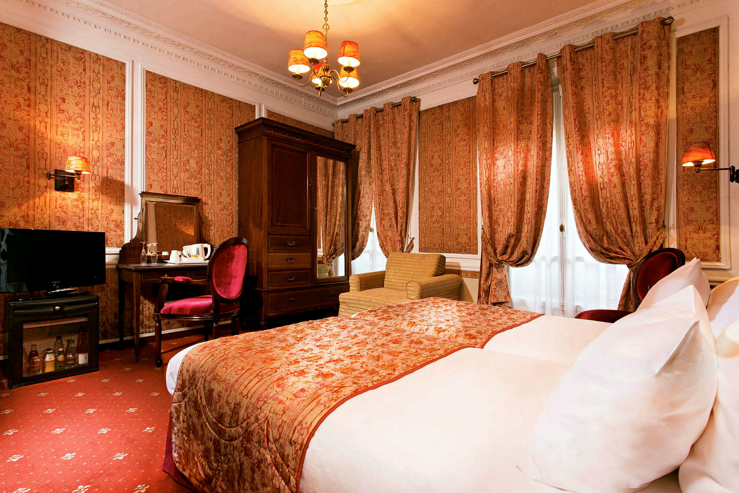 Et klassisk indrettet hotelværelse med en stor seng, gardiner, lænestol og et skrivebord med stol. (AI-genereret tekst)