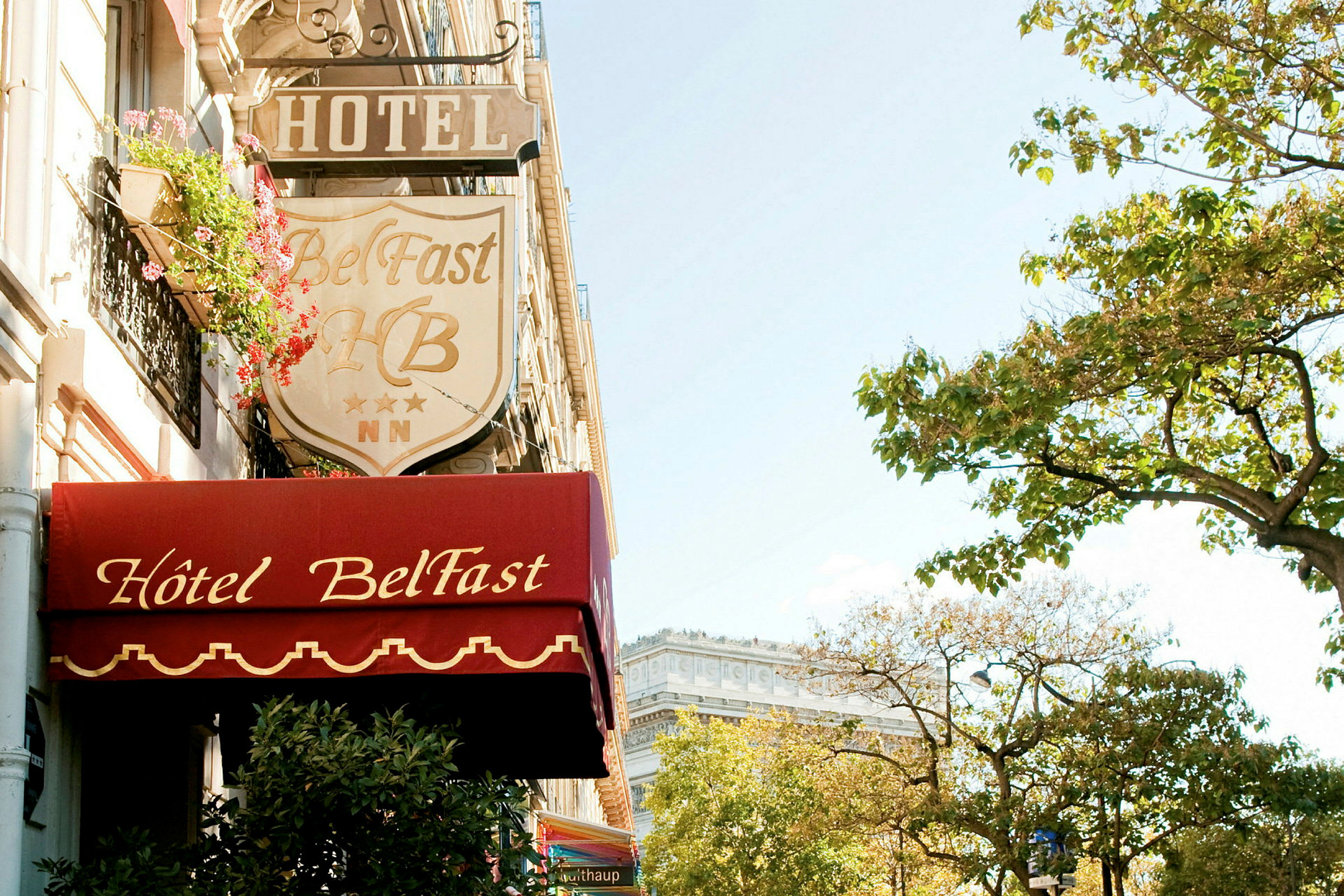Facaden af Hotel Belfast med skilte og træer i nærheden. (AI-genereret tekst)
