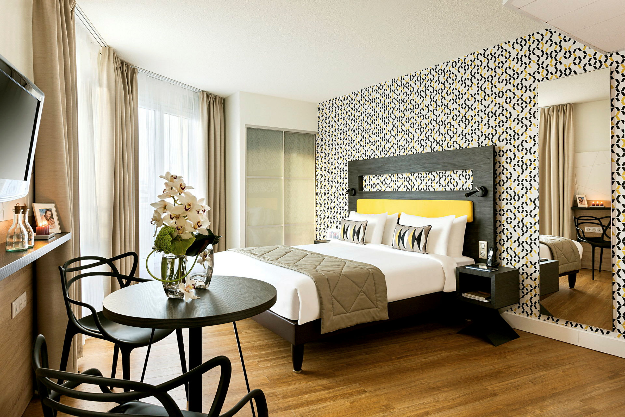 Et moderne hotelværelse med en dobbeltseng, farverigt tapet og siddeområde. (AI-genereret tekst)