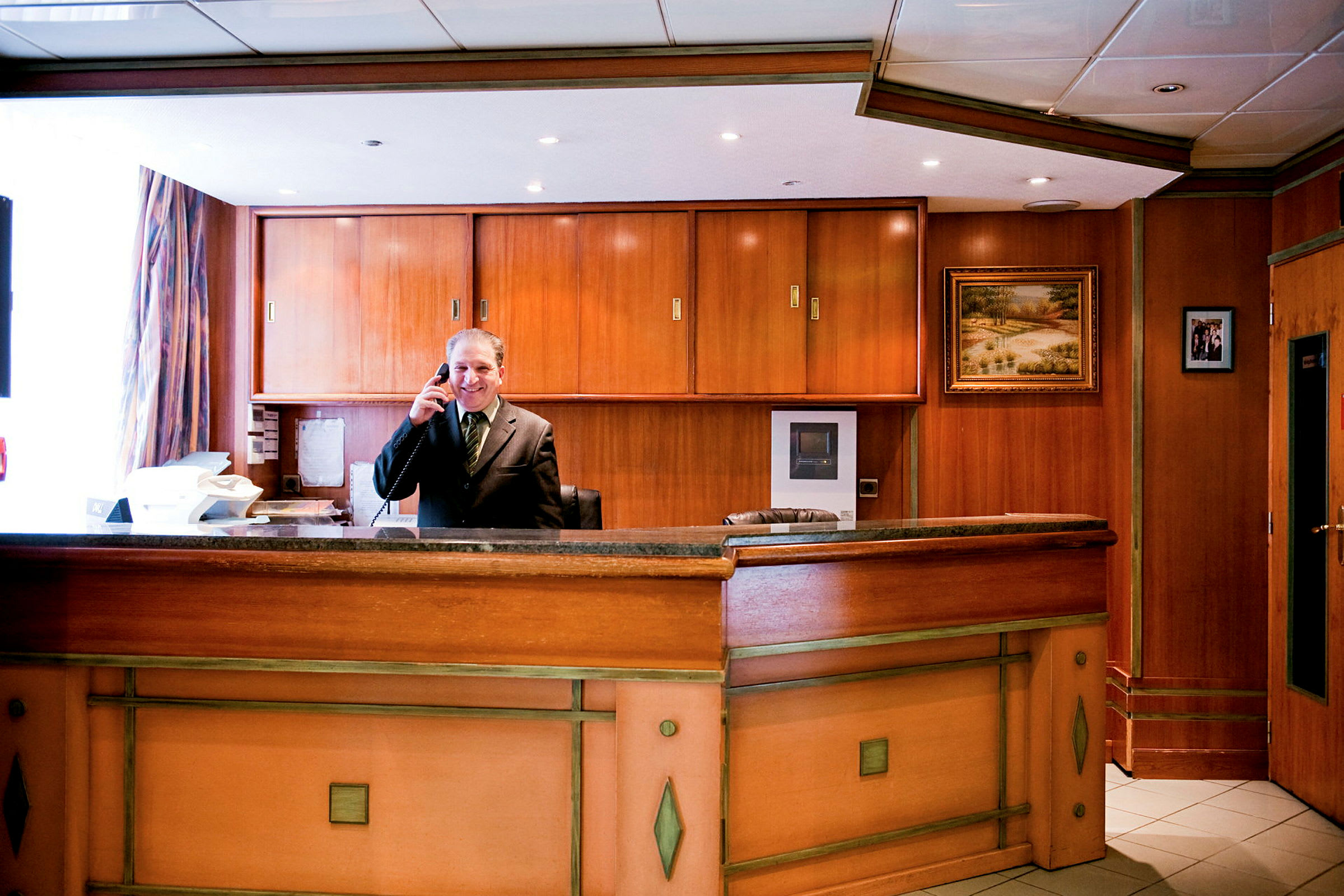 En hotelreception med træinteriør og en bordplade. (AI-genereret tekst)