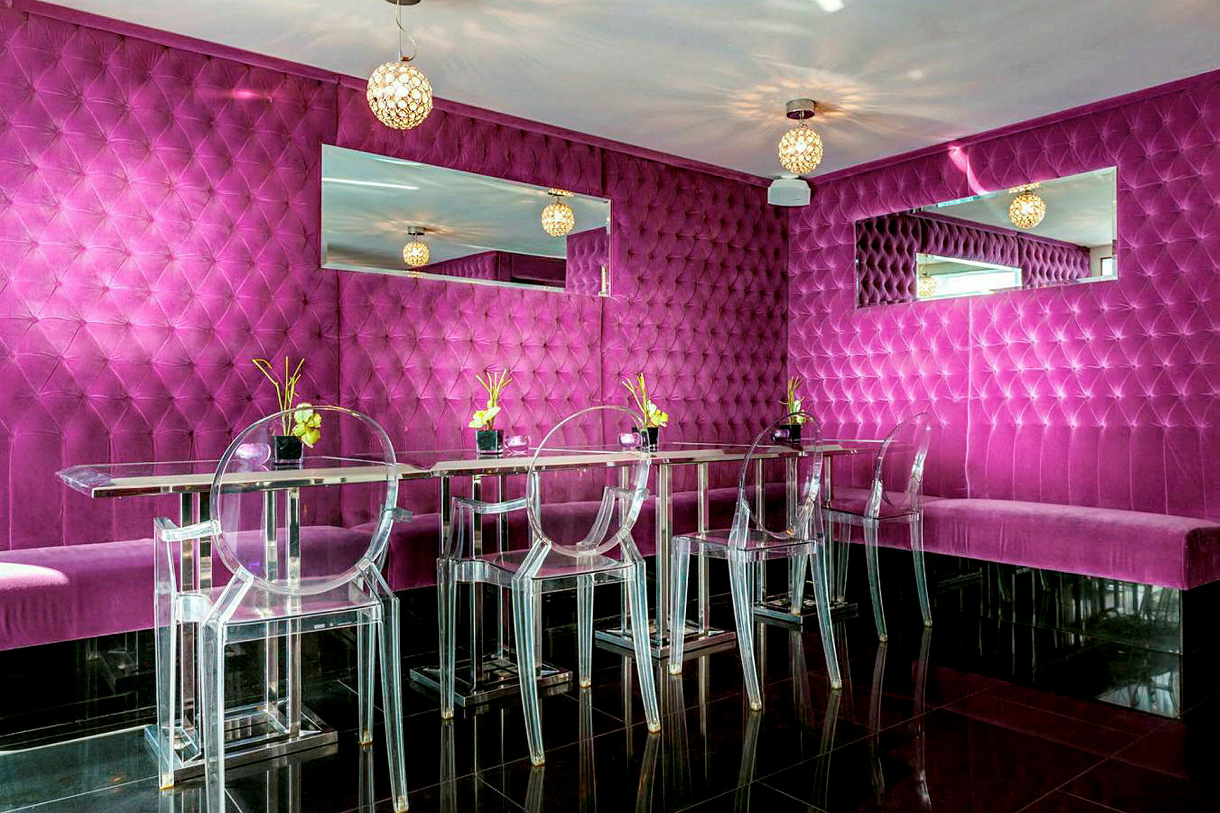 En moderne og farverig restaurant eller lounge med fuchsiafarvede vægpaneler, gennemsigtige stole og spejldekorationer. (AI-genereret tekst)