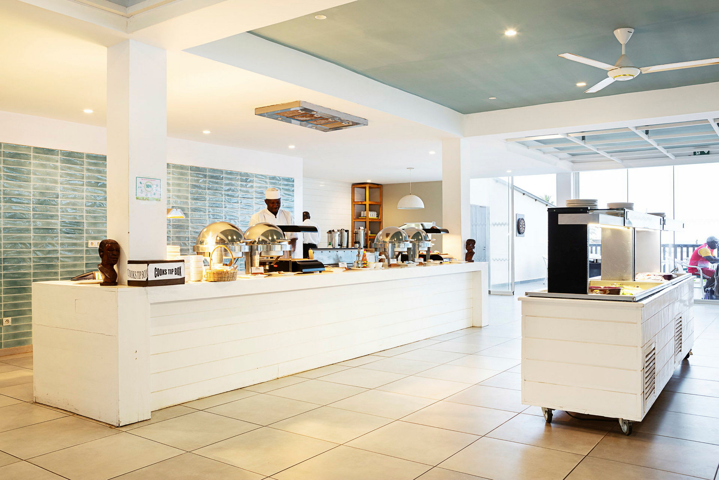 Billede af en lys buffetrestaurant med moderne detaljer og kok, der arbejder bag serveringsdisken. (AI-genereret tekst)