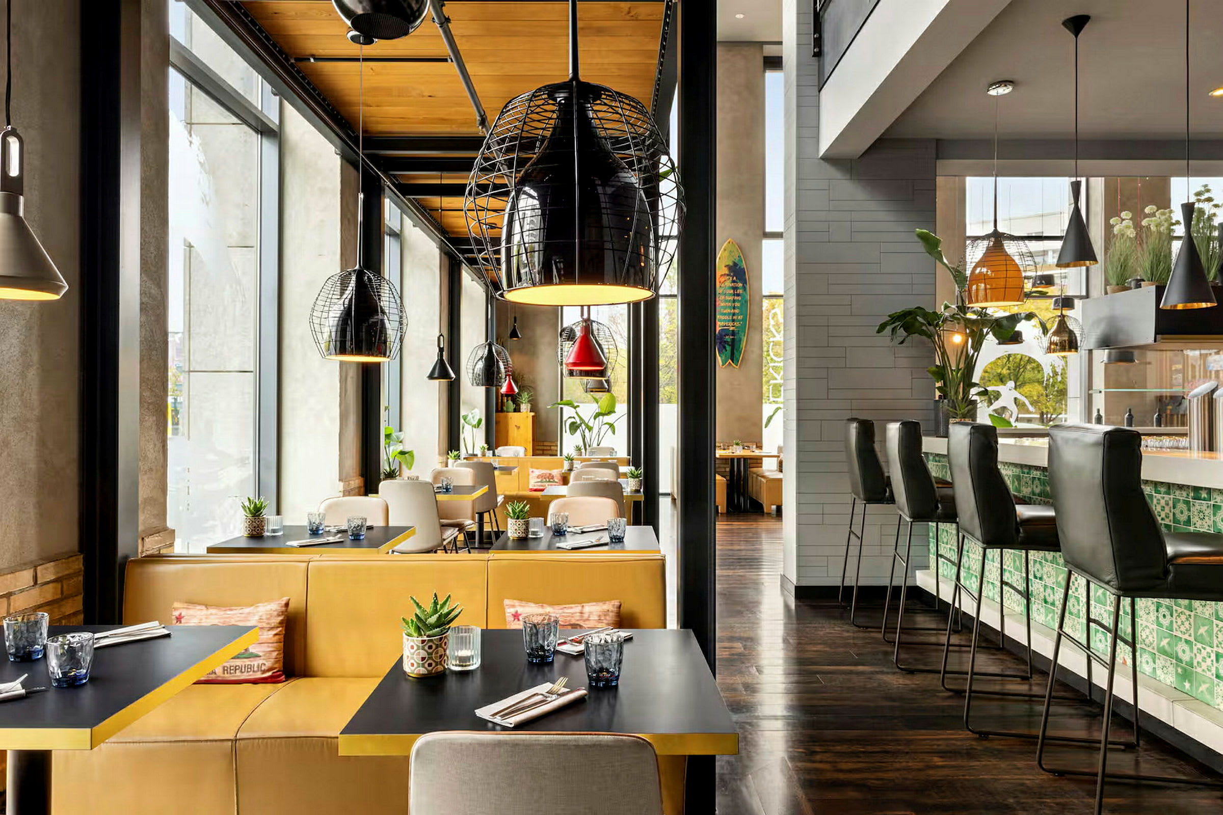 Interiør af en restaurant med siddepladser ved borde og en bardisk, dekoreret med moderne lamper og planter. (AI-genereret tekst)