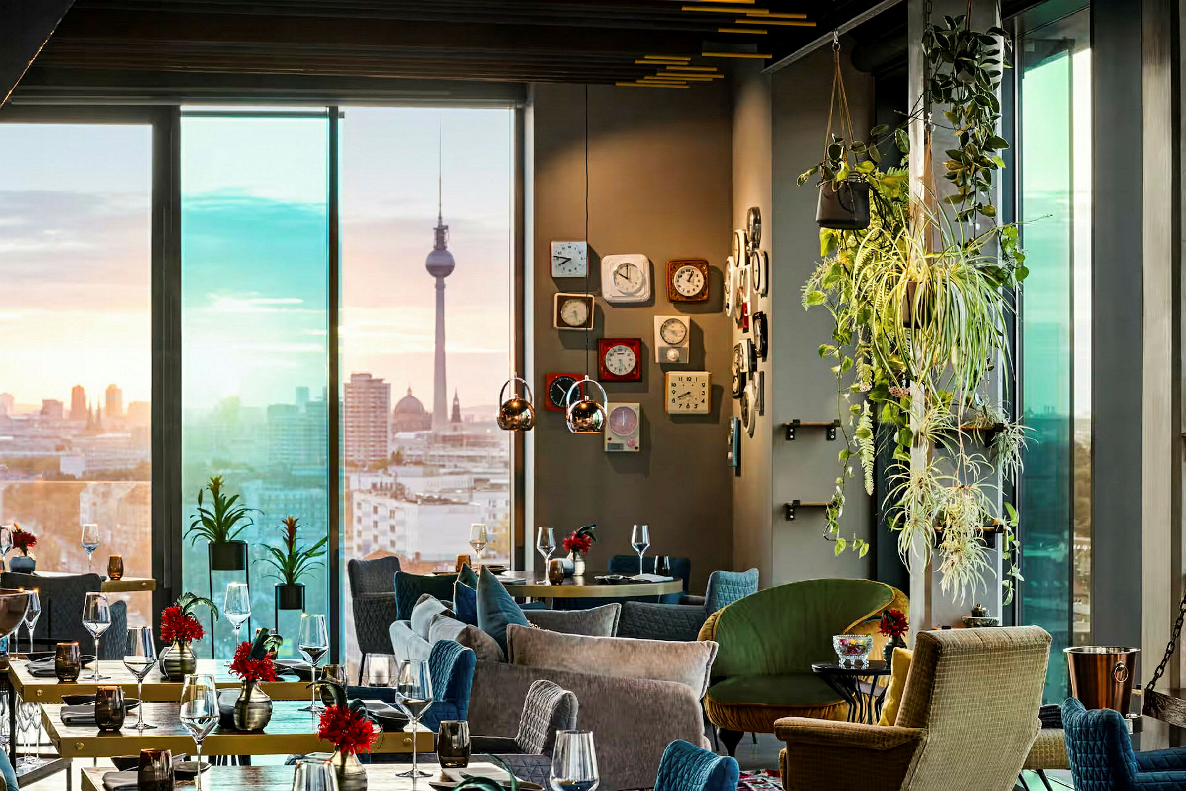 Et elegant restaurantinteriør med moderne møbler, grønne planter og udsigt over en bysilhuet med et vartegn i baggrunden. (AI-genereret tekst)