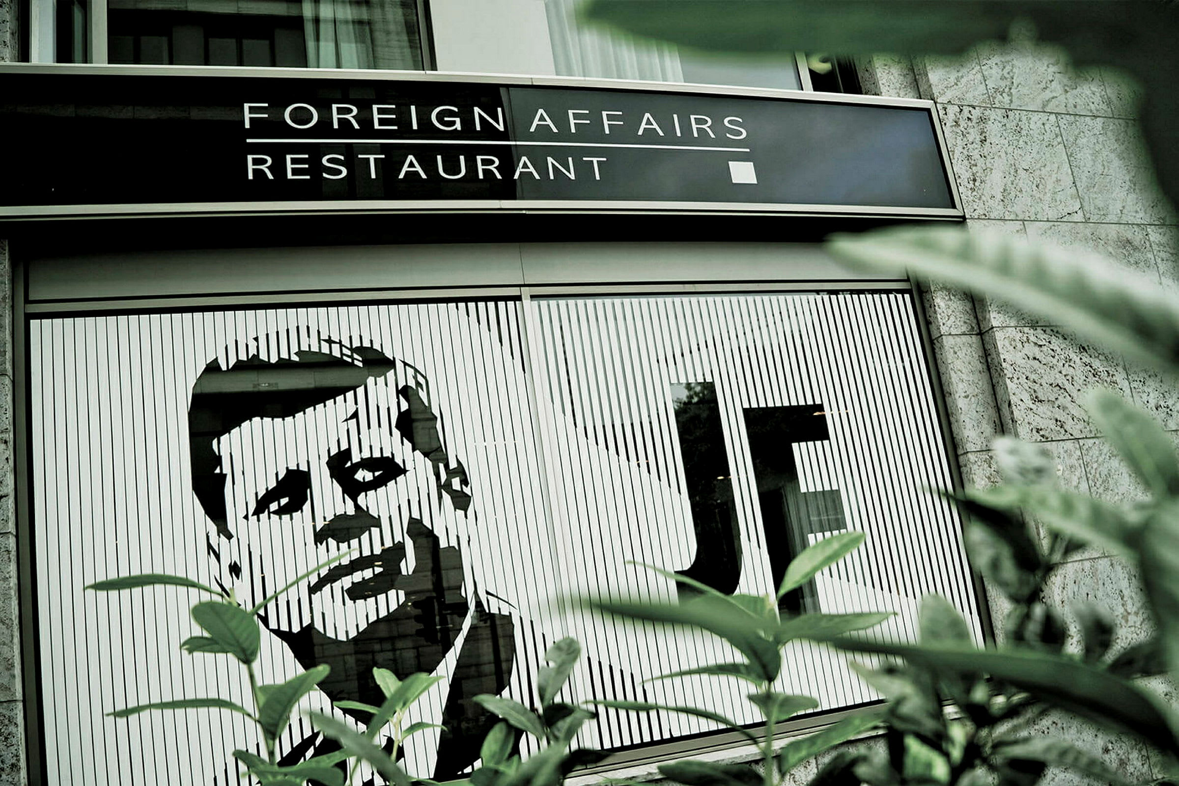 Billede af en restaurant med navnet 'Foreign Affairs Restaurant' og en illustration af en mand på bygningens facade. (AI-genereret tekst)