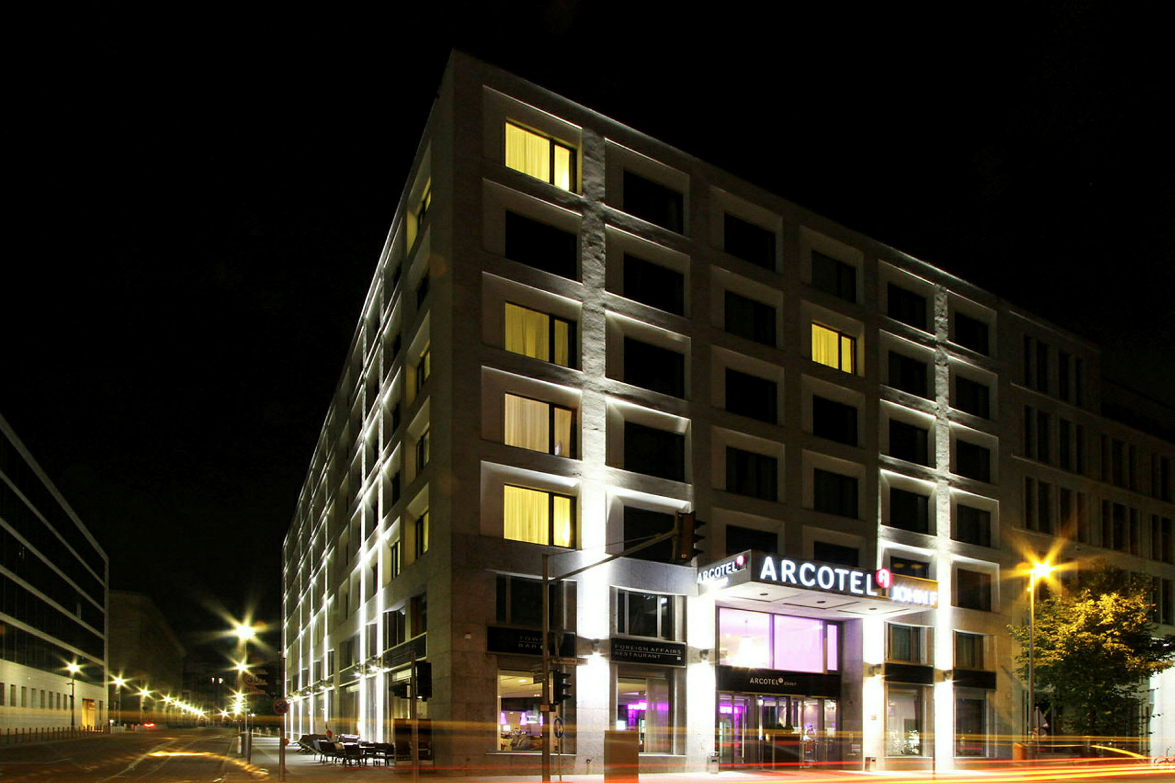 Et hotel oplyst om aftenen med Arcotel-skiltet ved indgangen. (AI-genereret tekst)