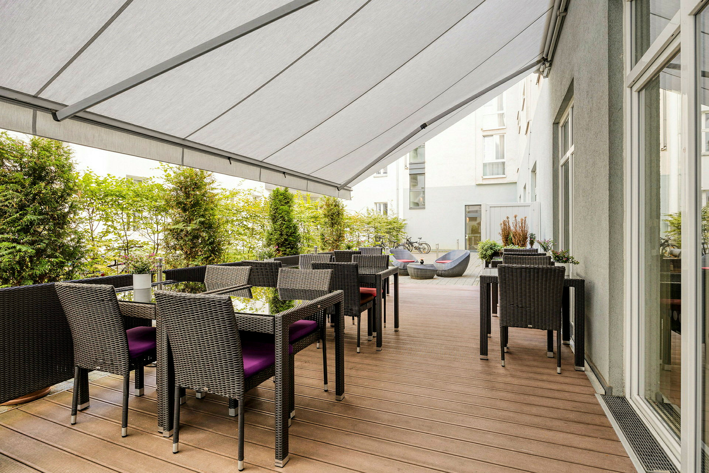 En terrasse med borde, stole og en overdækkende markise. (AI-genereret tekst)