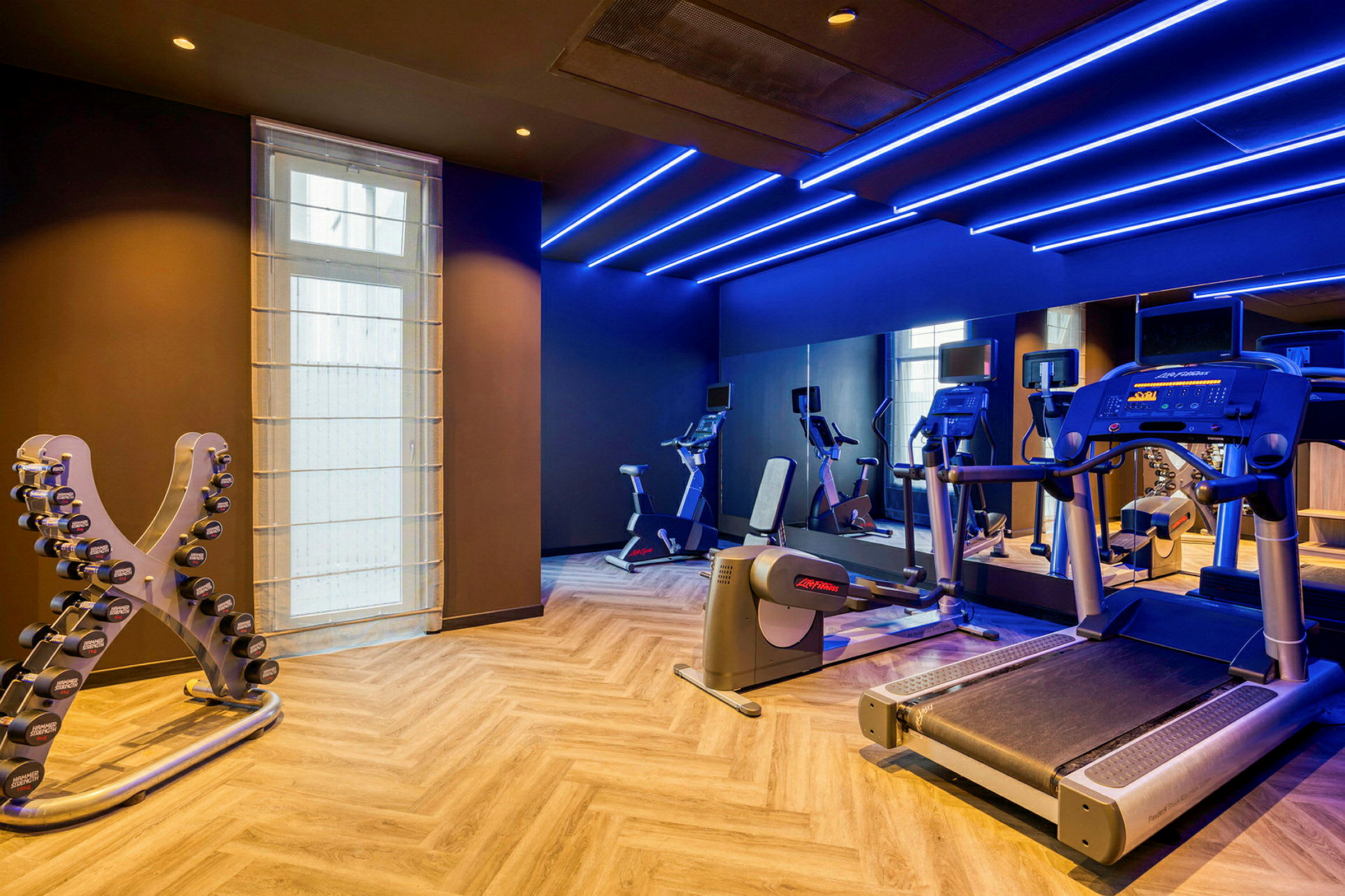 Et fitnesscenter med træningsudstyr inklusive løbebånd, motionscykler og håndvægte. (AI-genereret tekst)