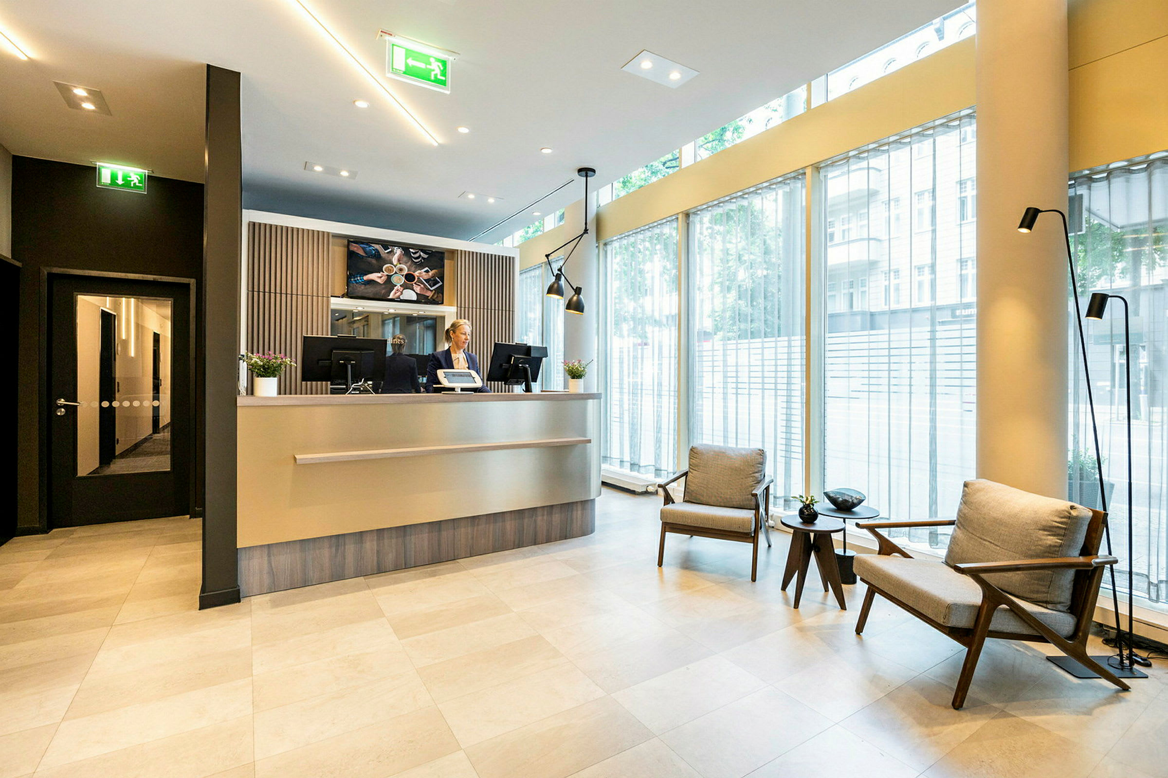 Hotelreception med siddeområde og store vinduer. (AI-genereret tekst)