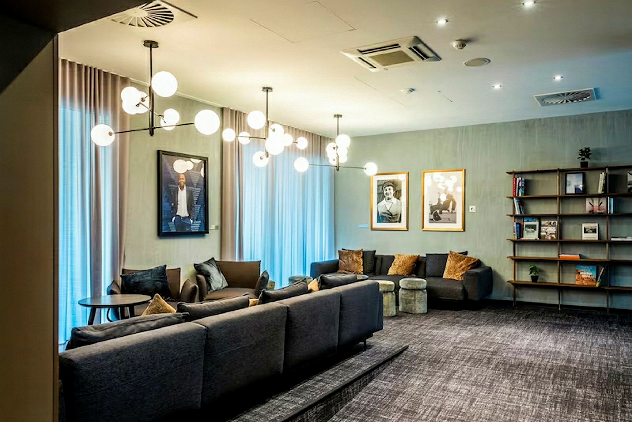 En elegant stue med moderne sofaer, dekorative lamper og kunstværker på væggene. (AI-genereret tekst)