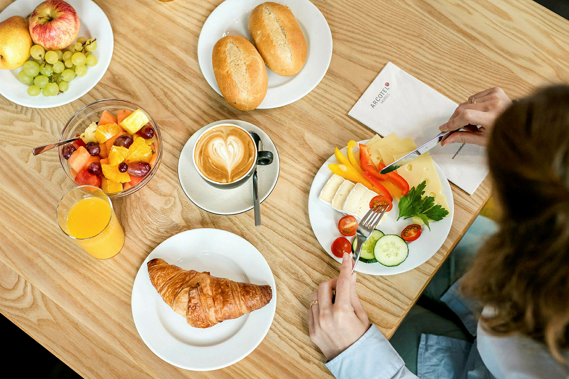 En morgenmad med kaffe, croissant, frugtsalat, ost, grøntsager og brød. (AI-genereret tekst)