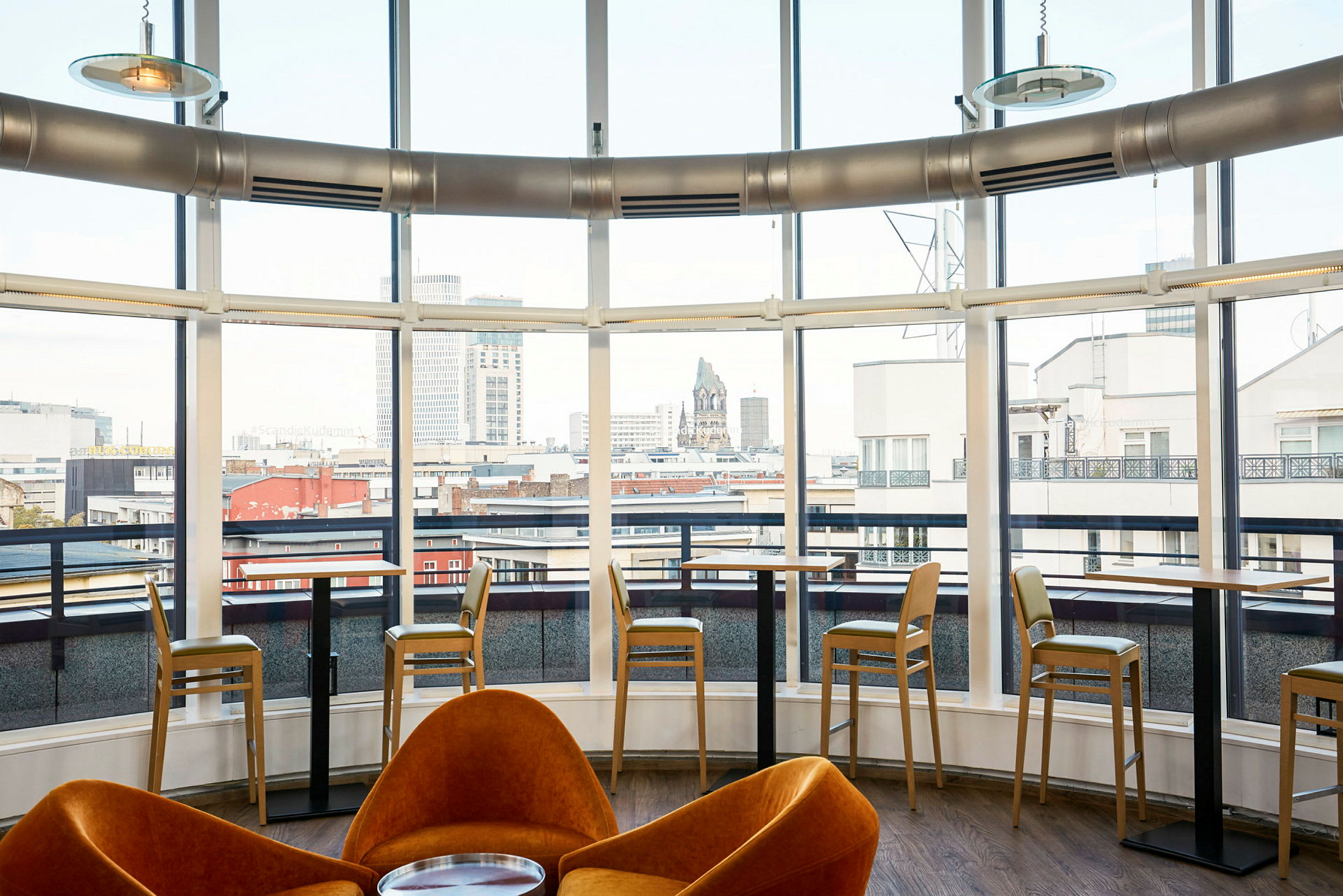 Indendørs udsigt over en moderne café med store vinduer mod byen. (AI-genereret tekst)