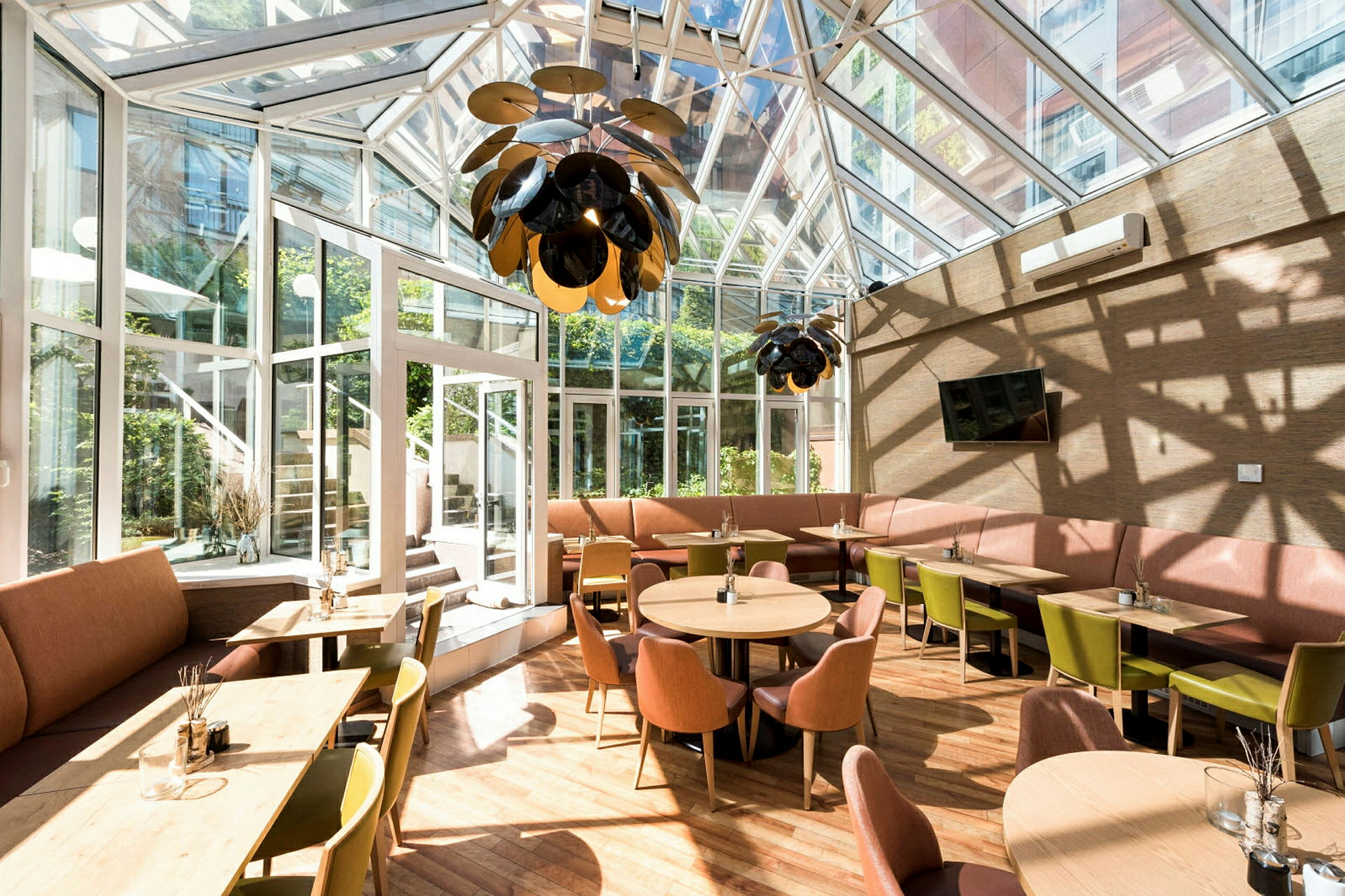 En lyst møbleret café med store vinduer og glastag. (AI-genereret tekst)