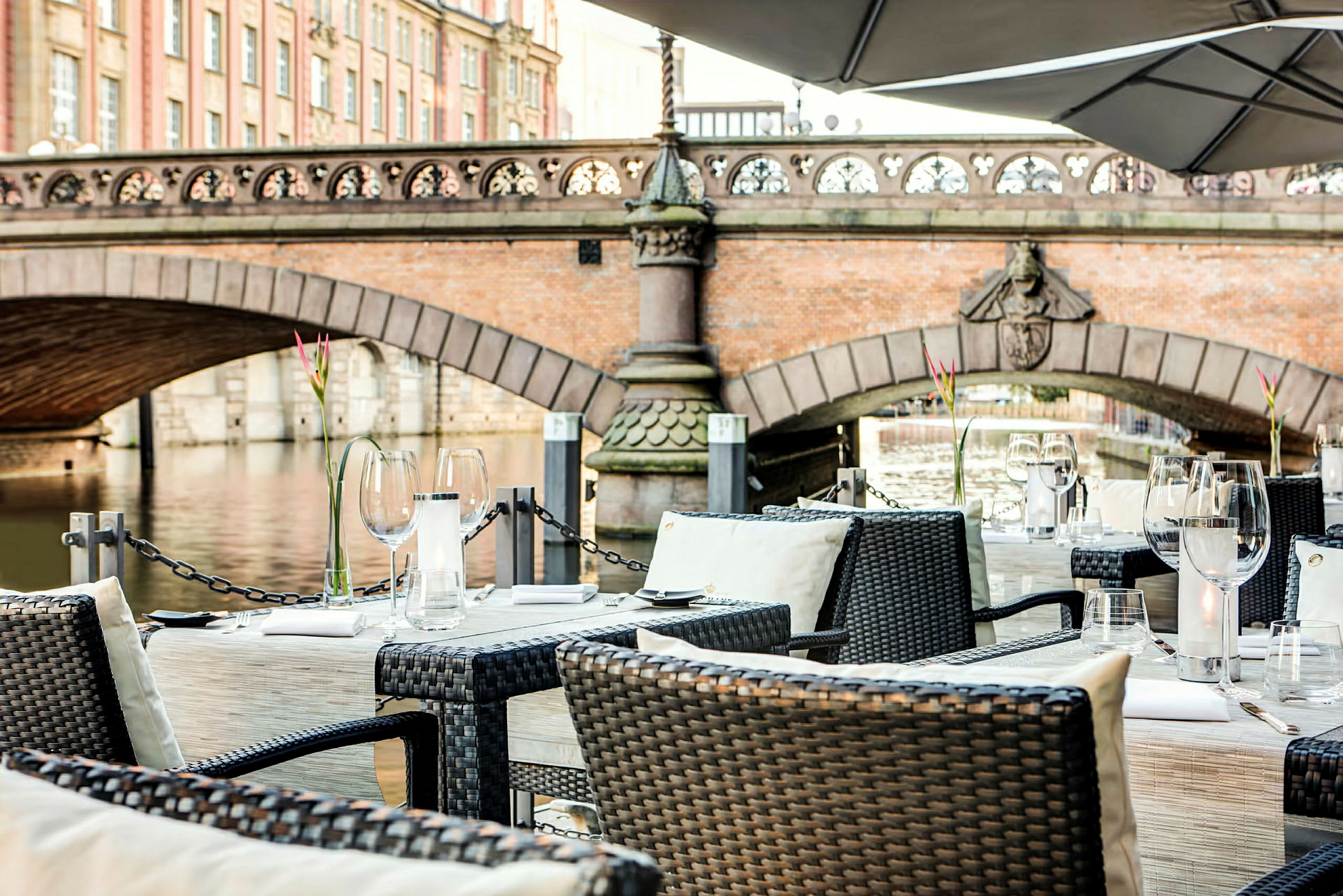 Velplacerede borde på en terrasse med udsigt over en bro og en flod. (AI-genereret tekst)