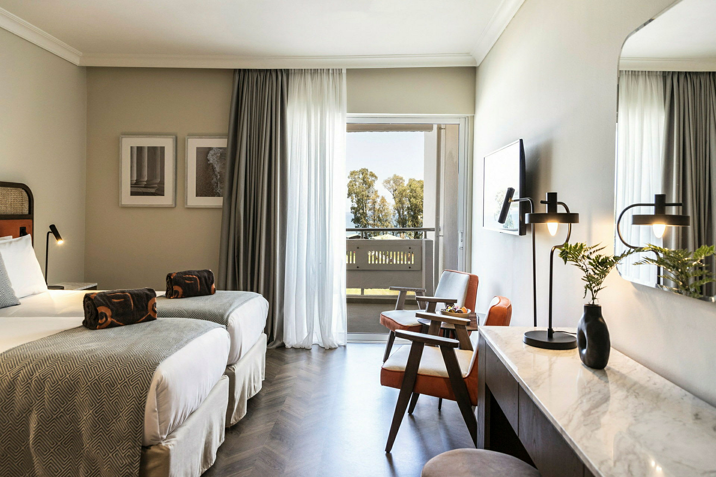 Hotelværelse med to enkeltsenge, siddeområde og skrivebord. Balkon med udsigt over træer. (AI-genereret tekst)