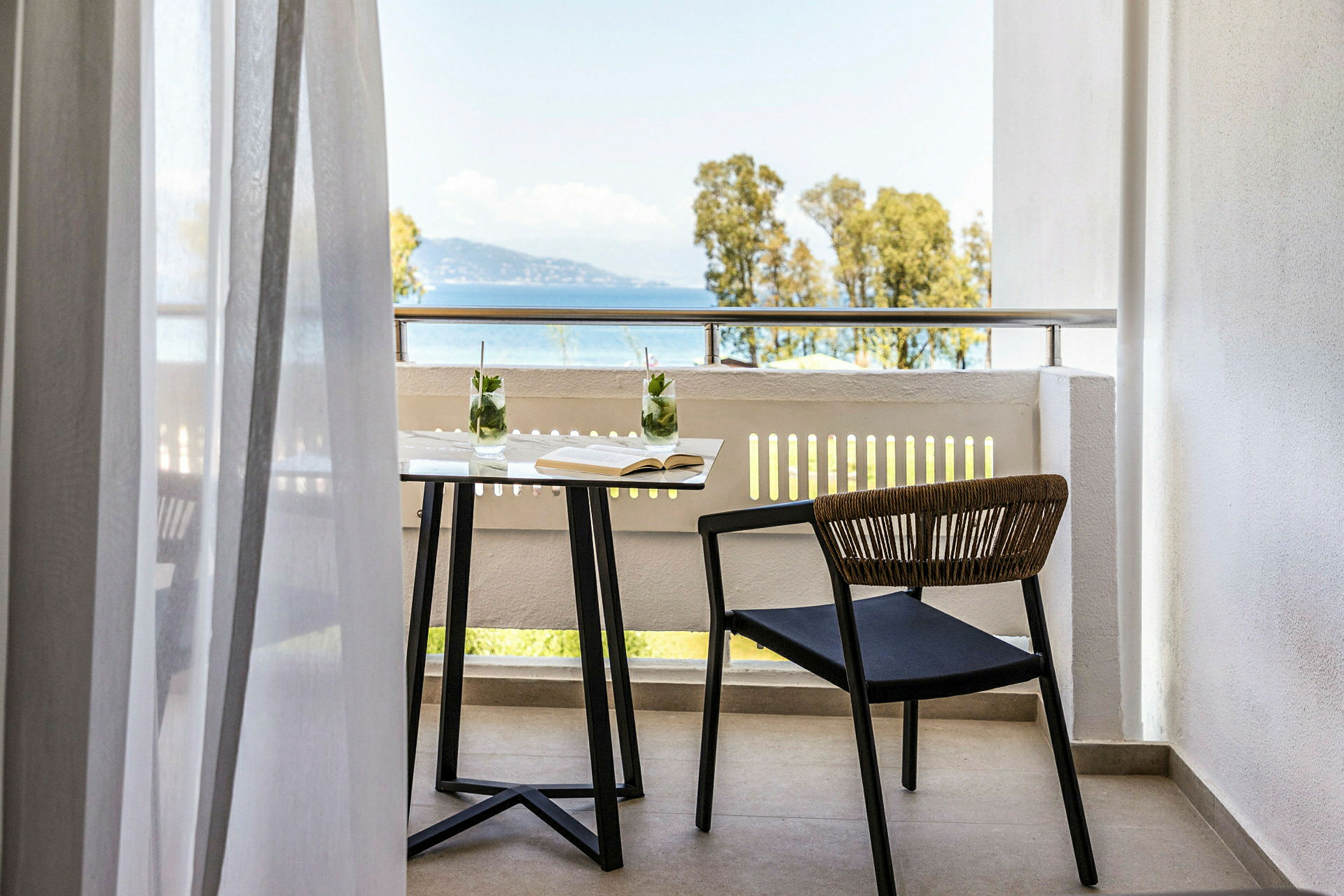 En balkon med bord, stol og udsigt til havet. (AI-genereret tekst)