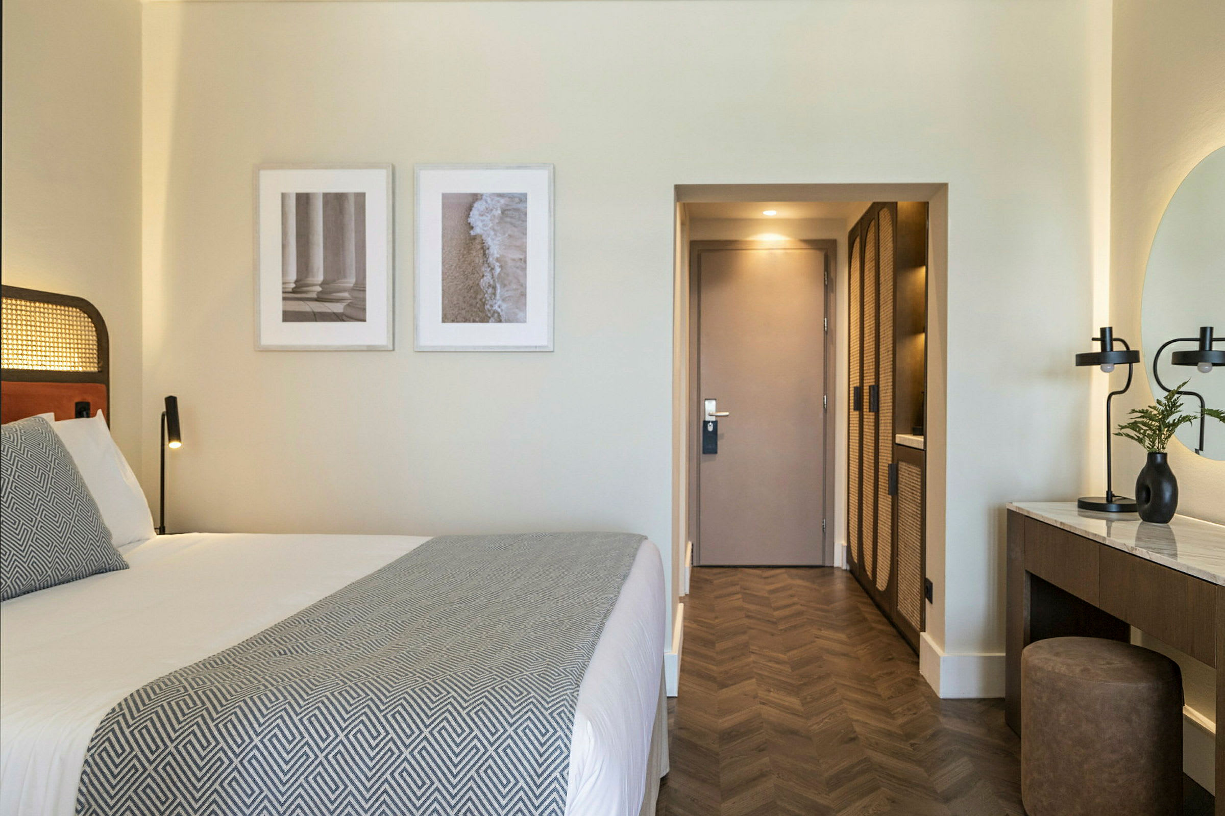 Et velordnet hotelværelse med en dobbeltseng, kunstværker på væggen og et skrivebordsmøbel. (AI-genereret tekst)
