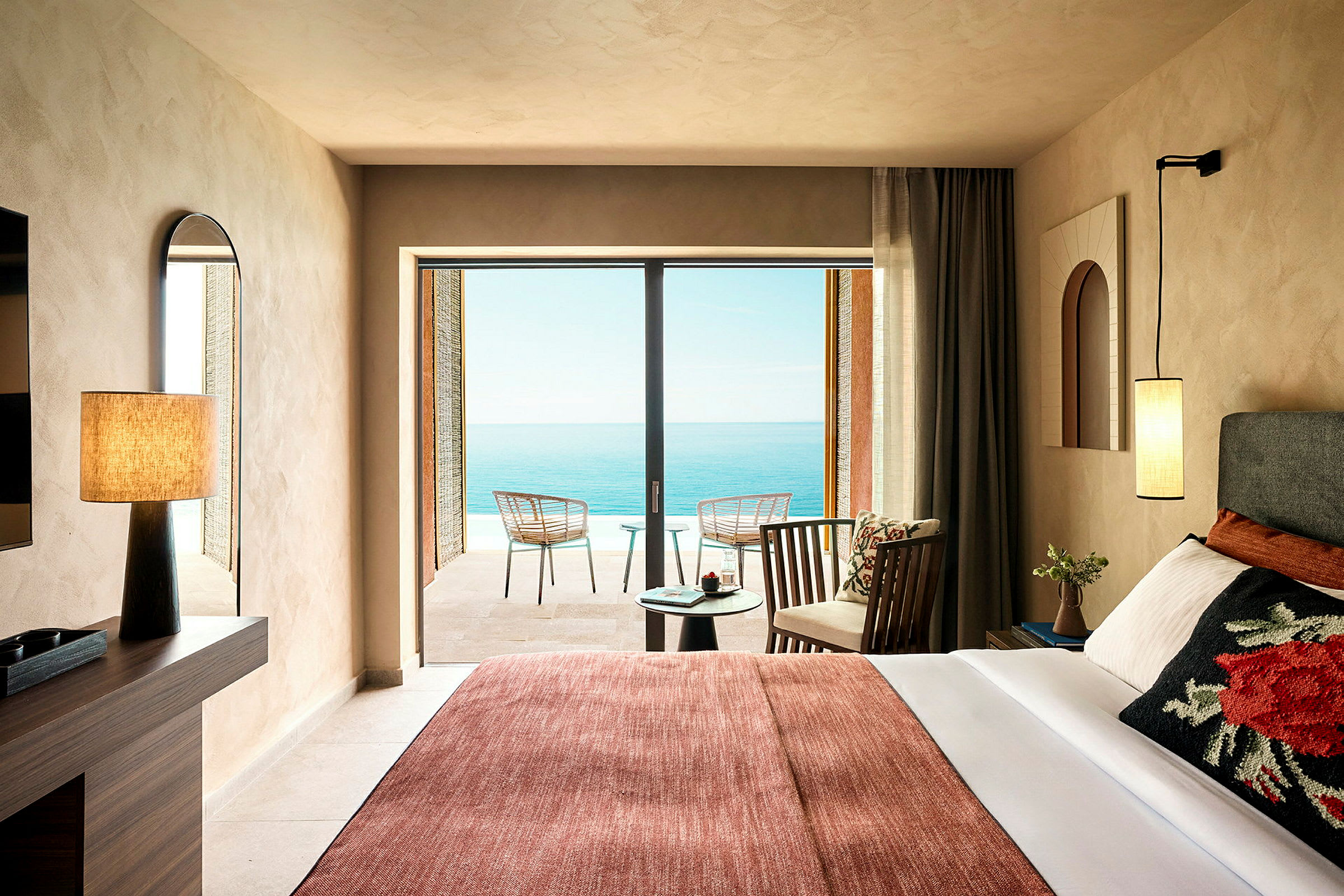 Et hotelværelse med en seng, en lænestol og en balkon med udsigt over havet. (AI-genereret tekst)
