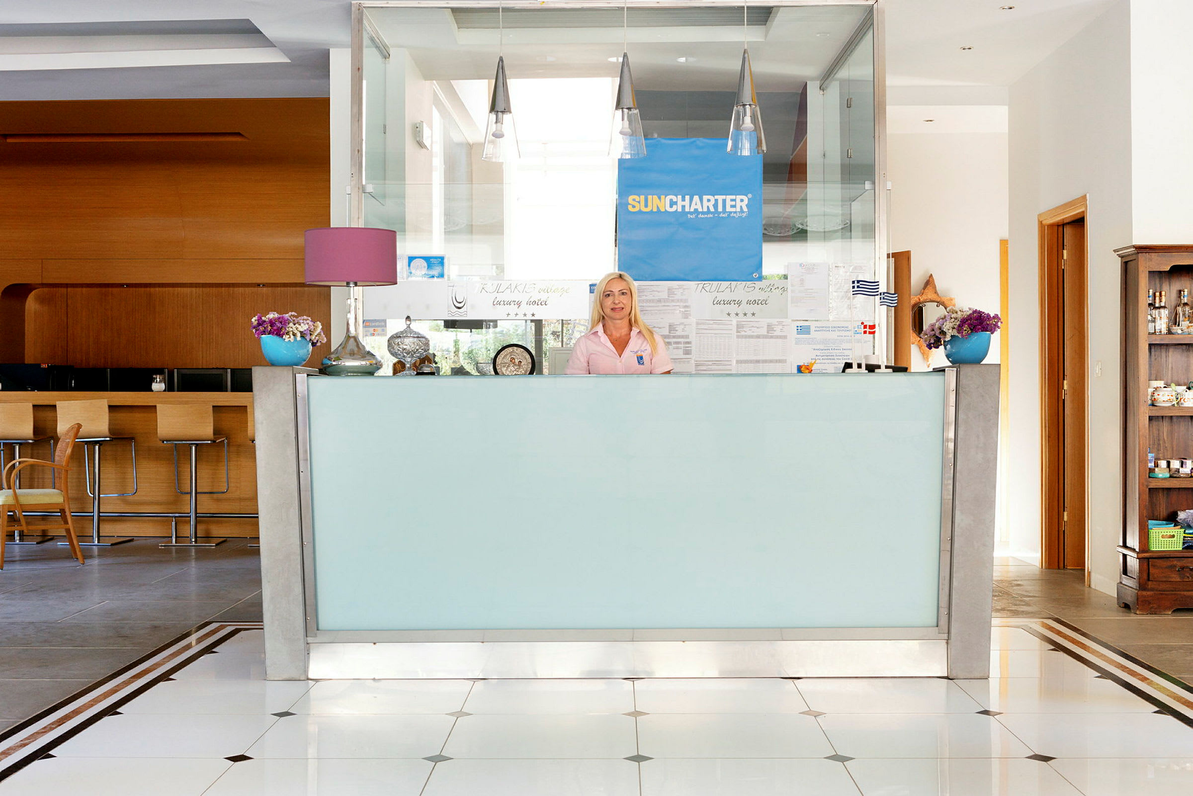 Billede af en receptionsdisk med en person bagved. Indretningen inkluderer blomster og dekorative genstande. (AI-genereret tekst)