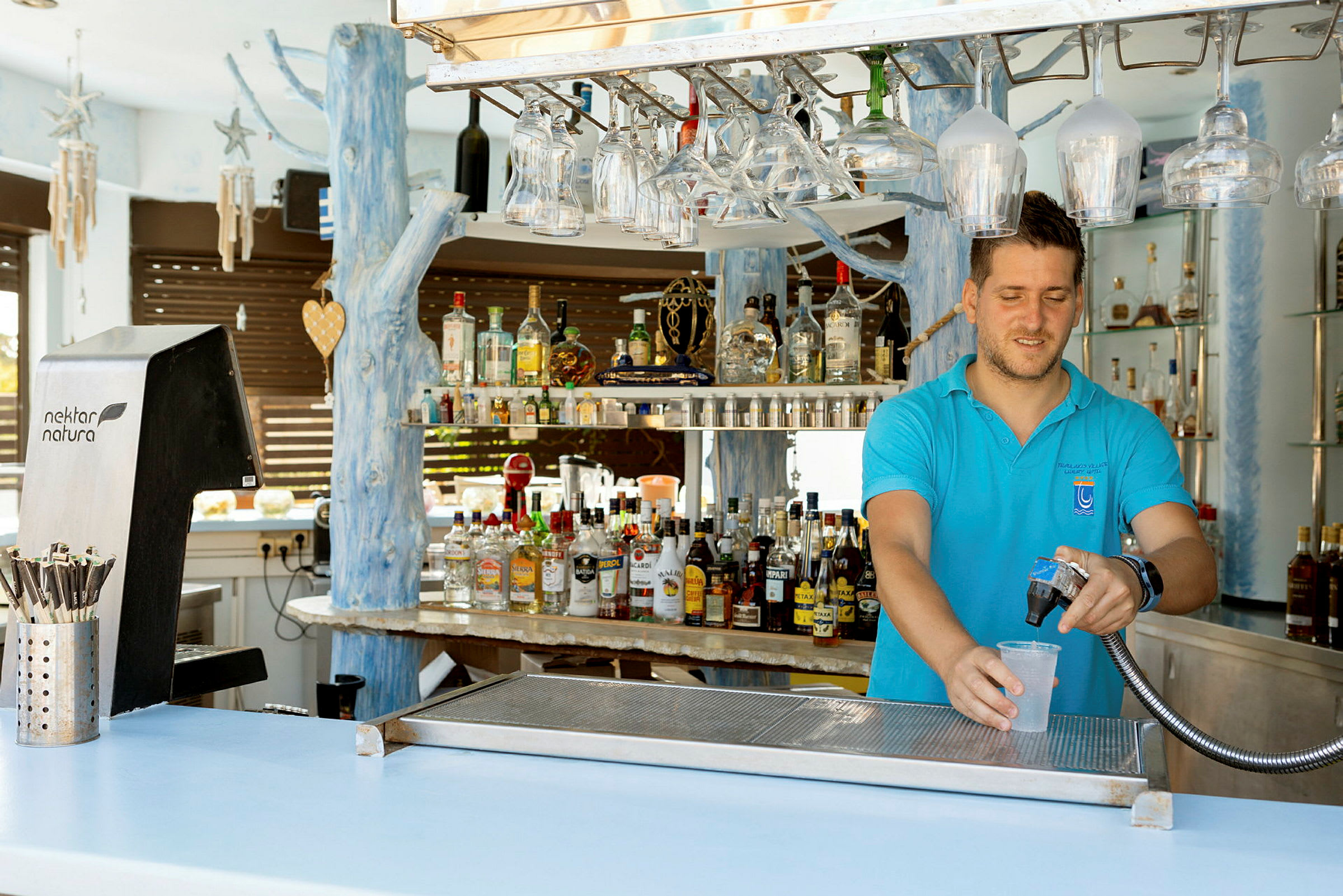 En bartender fylder et glas med en drik ved en bar. (AI-genereret tekst)
