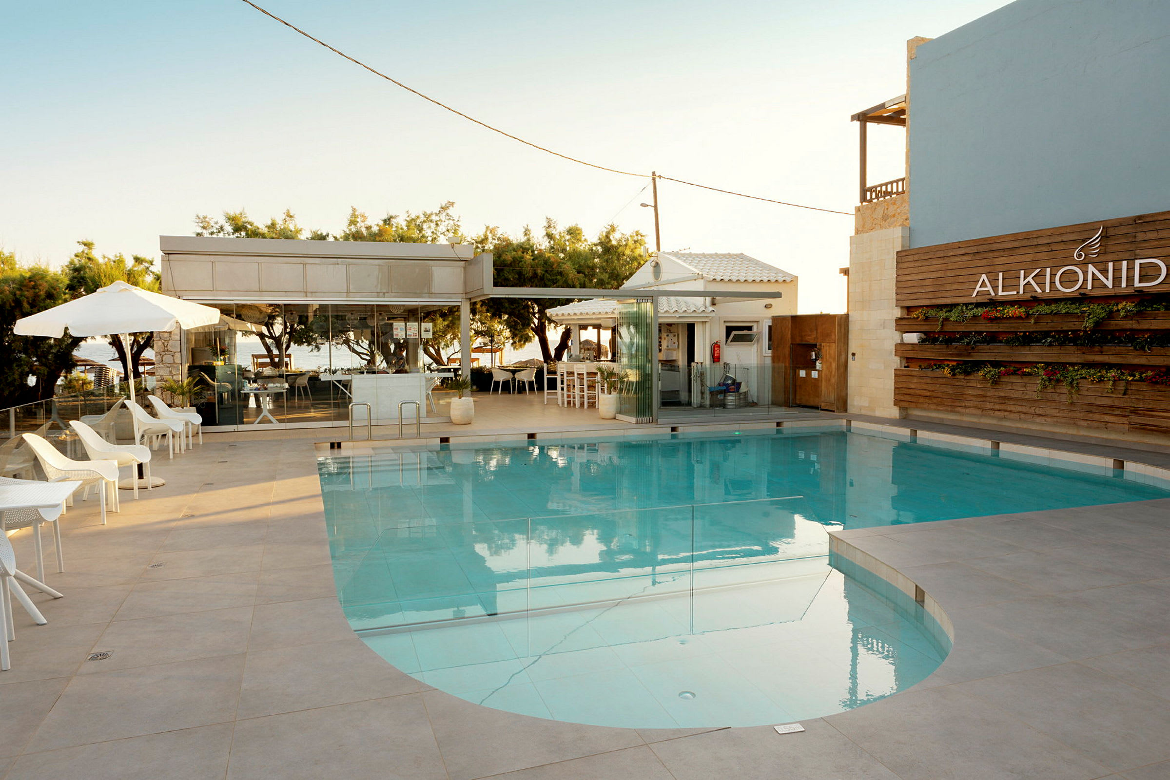 En swimmingpool med liggestole og parasoller ved siden af samt en bygning i baggrunden. (AI-genereret tekst)