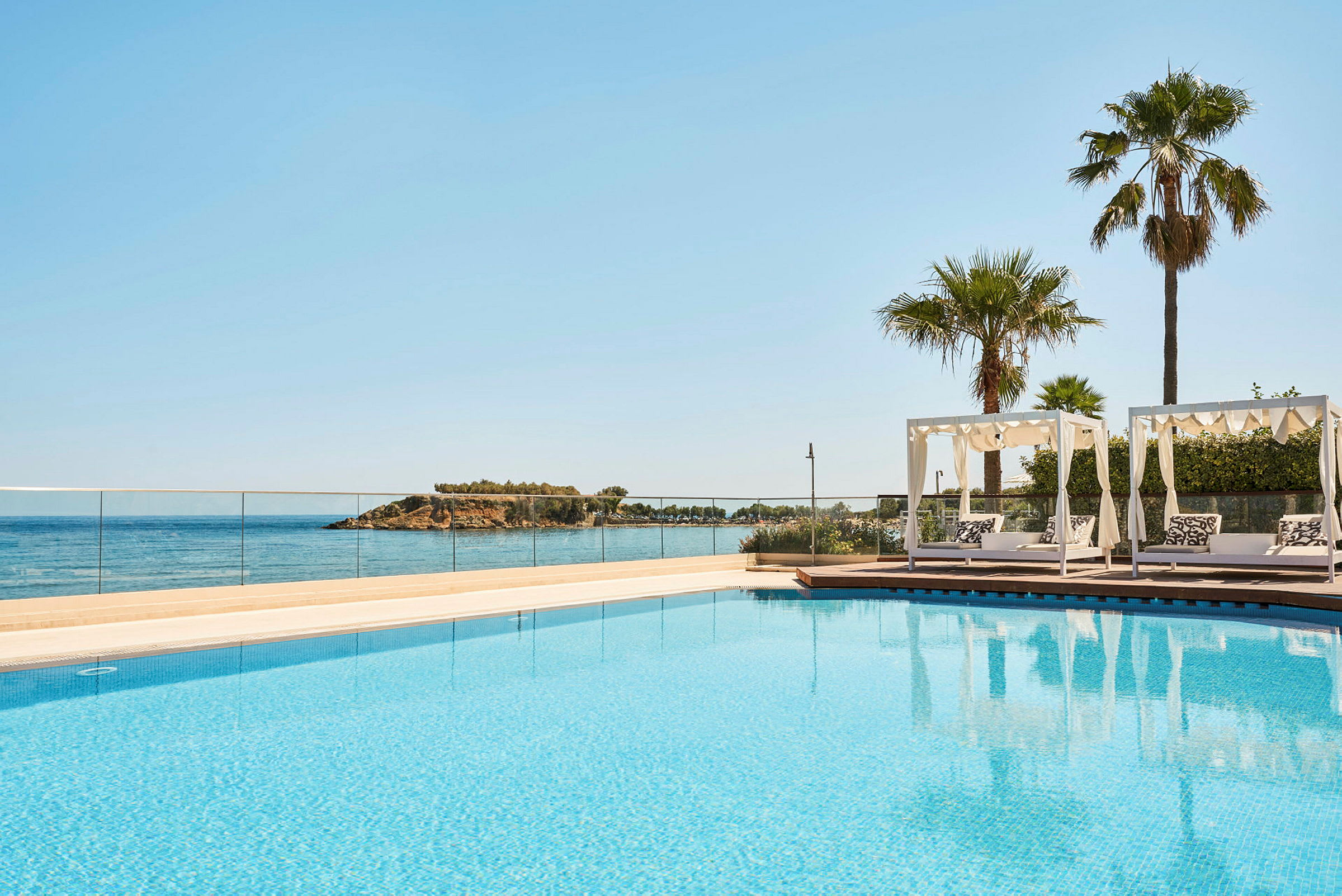 Udendørs pool med udsigt over havet og liggestole under pergola. (AI-genereret tekst)