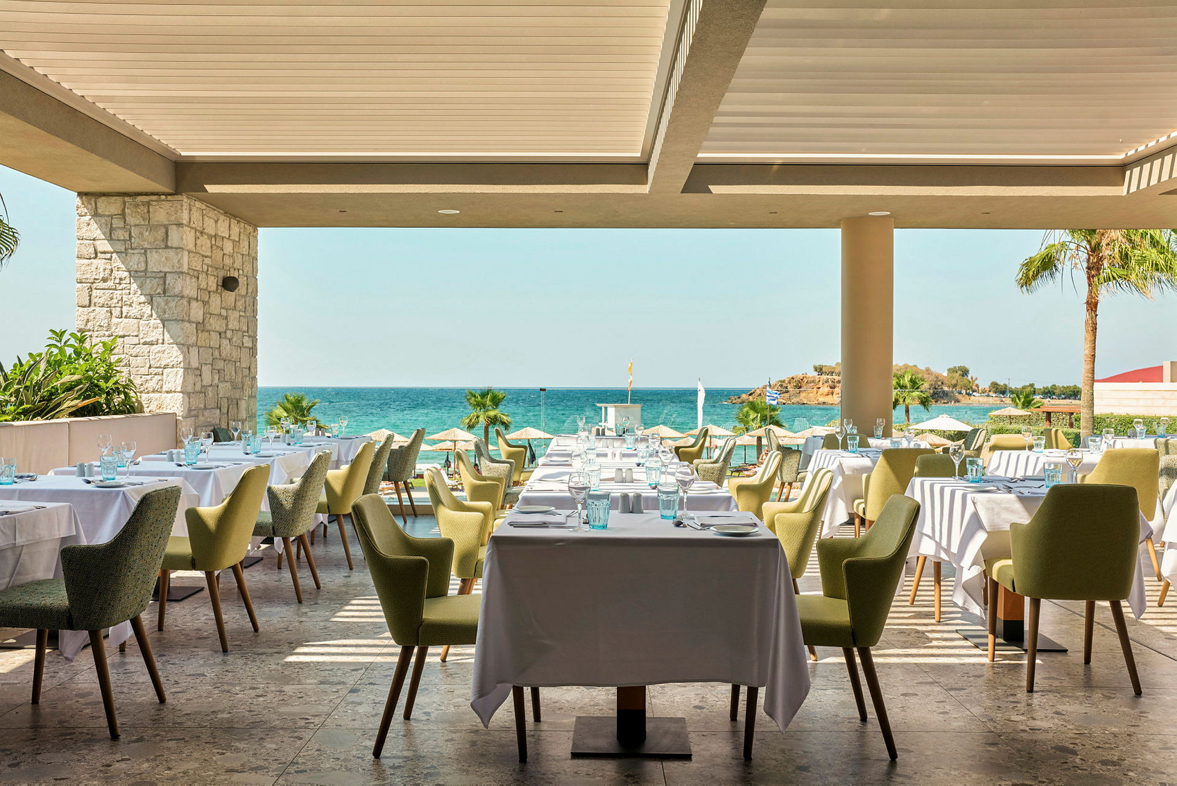 Restaurant med dækkede borde og udsigt til havet. (AI-genereret tekst)