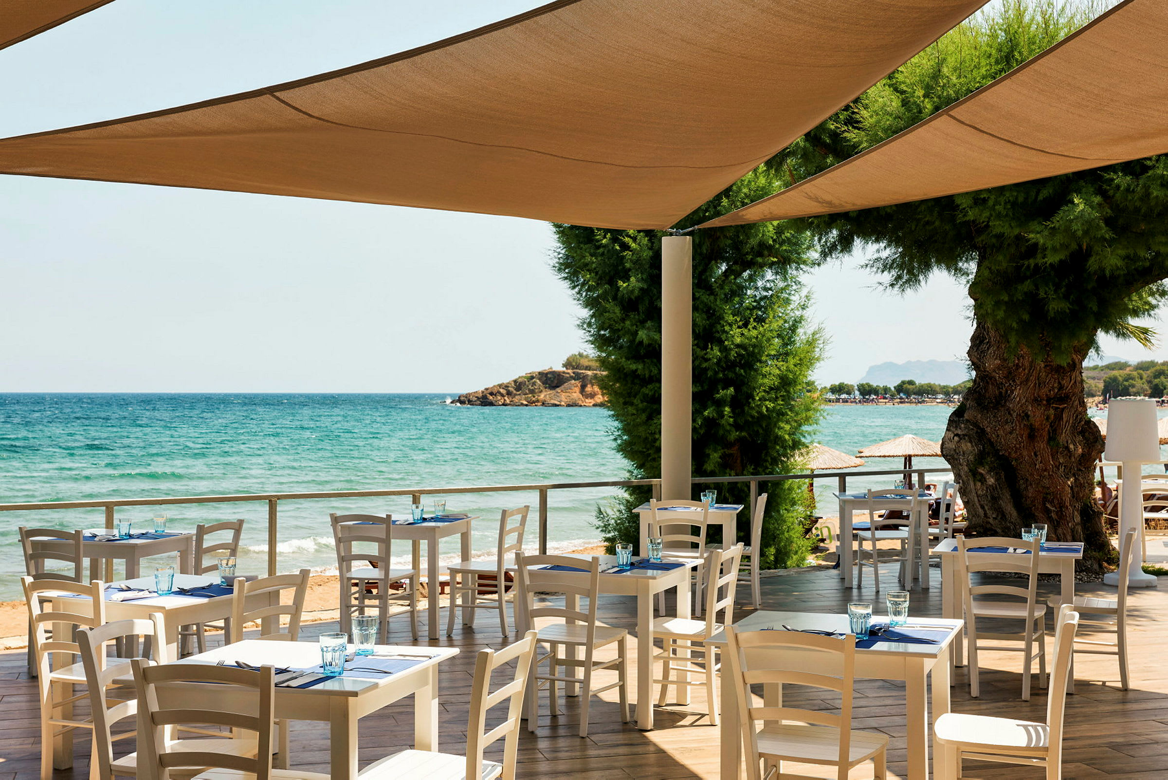 Restaurant med hvide borde og stole ved havet. (AI-genereret tekst)