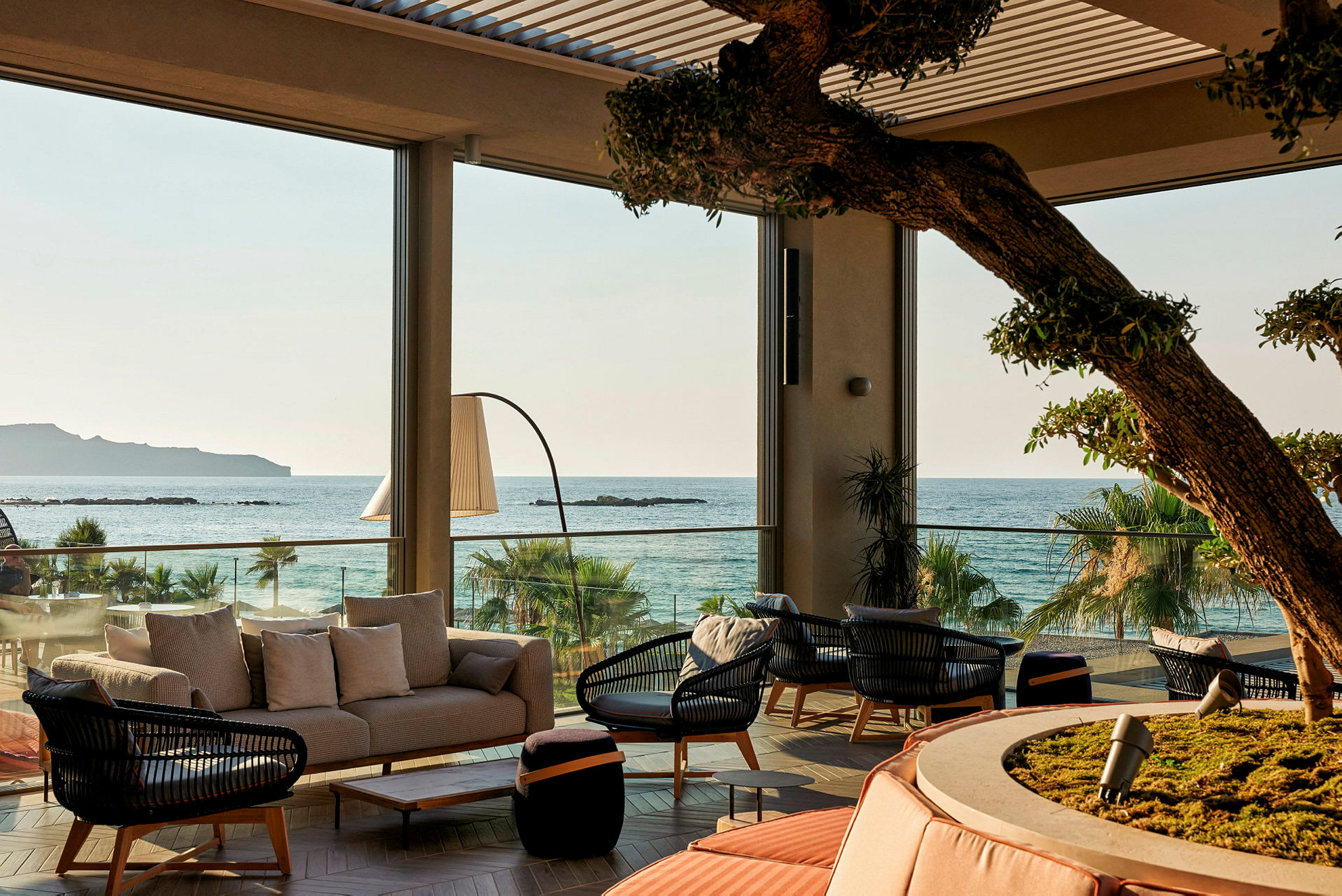 Udsigt over en møbleret lounge med havet i baggrunden. (AI-genereret tekst)
