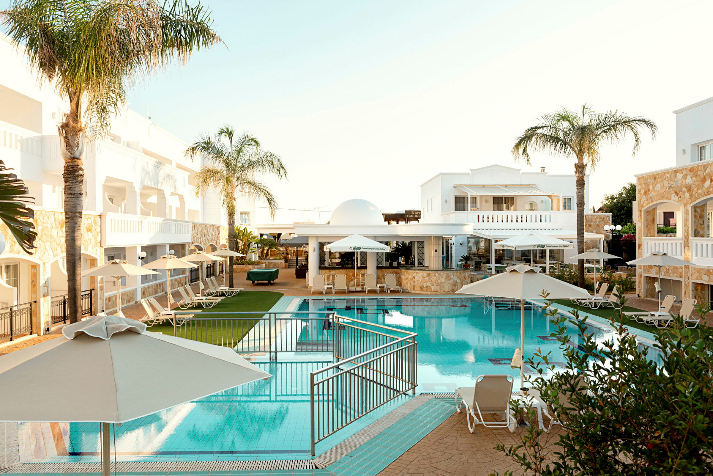 Hotelområde med pool, liggestole og parasoller. (AI-genereret tekst)