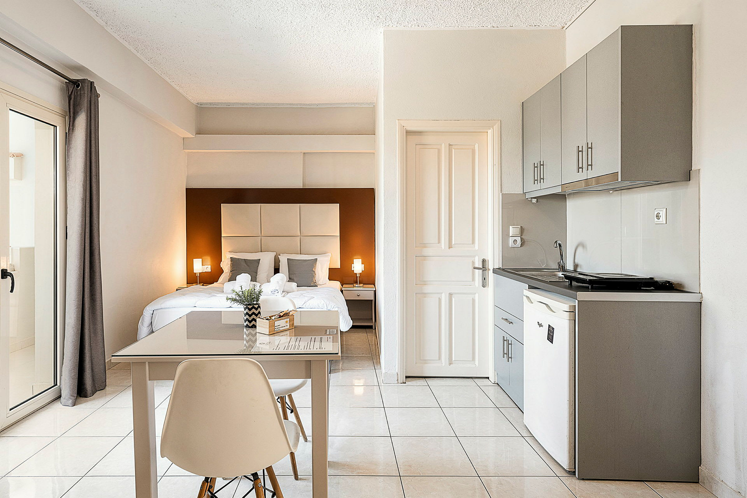 Et lyst og moderne hotelværelse med dobbeltseng, et lille spisebord og et tekøkken. (AI-genereret tekst)