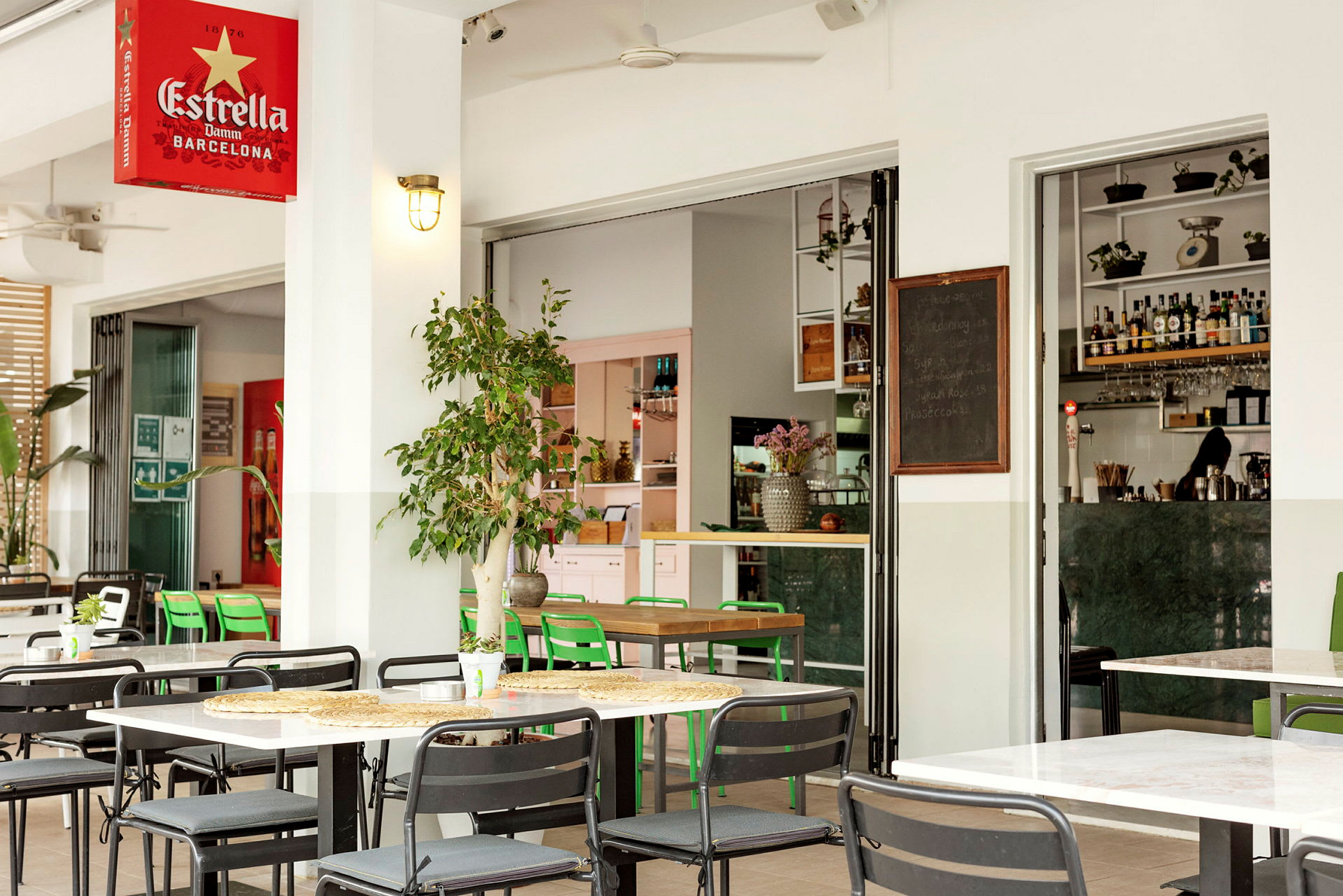 Udendørs serveringsområde med borde og stole og åben indgang til en moderne bar. (AI-genereret tekst)