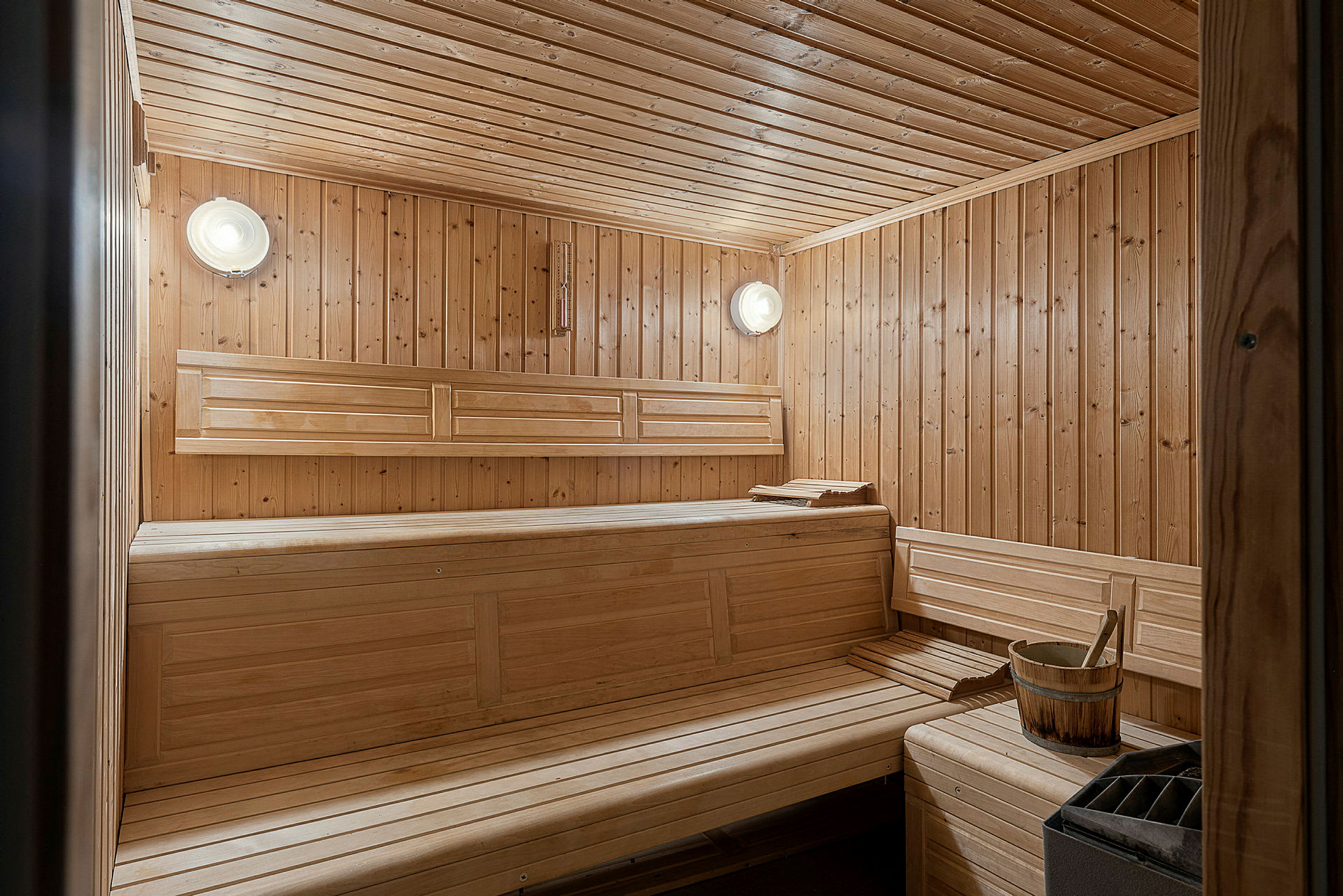 En træfyret sauna med træpaneler og bænke. (AI-genereret tekst)