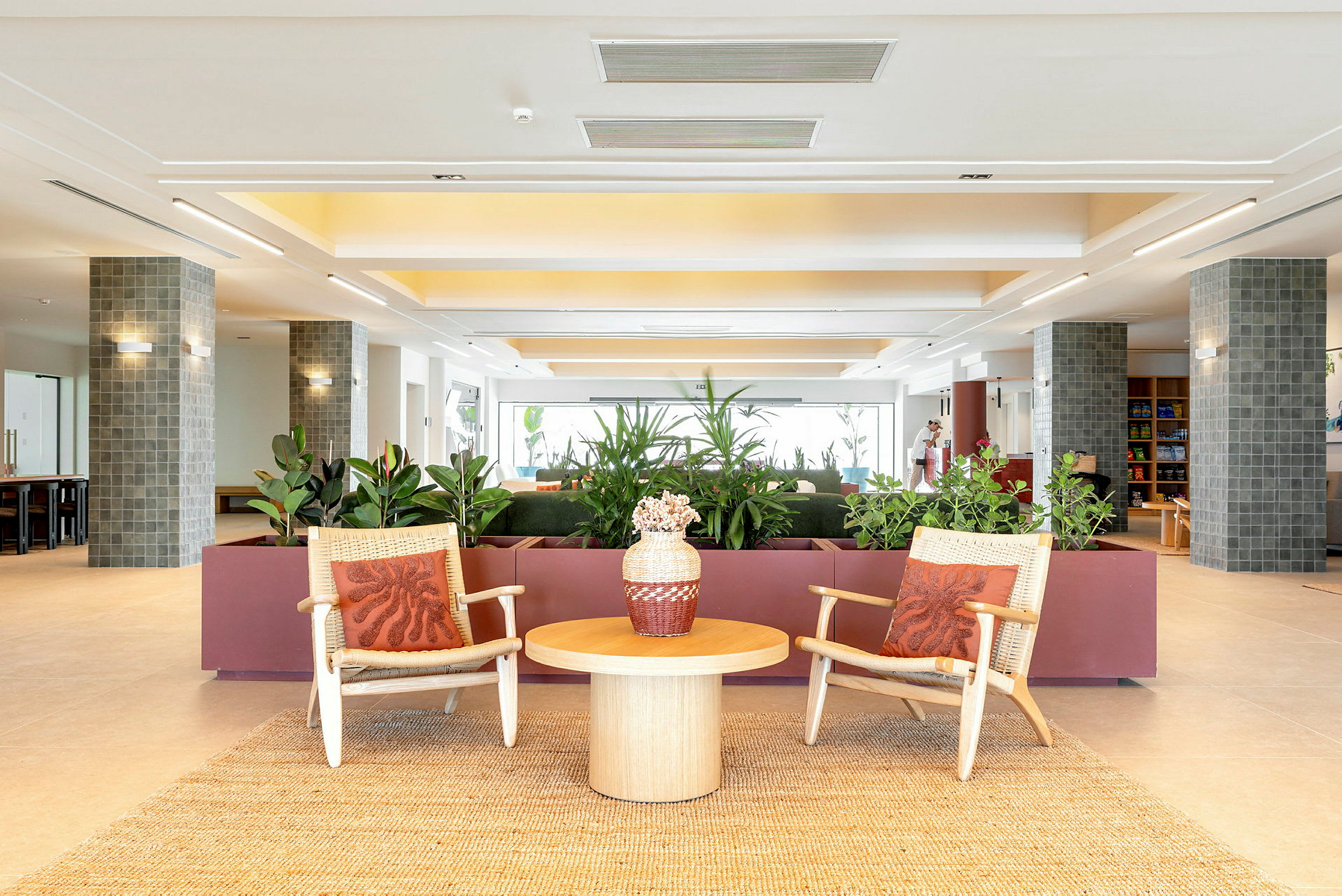 Billede af en moderne hotellobby med to stole, et bord og planter i baggrunden. (AI-genereret tekst)