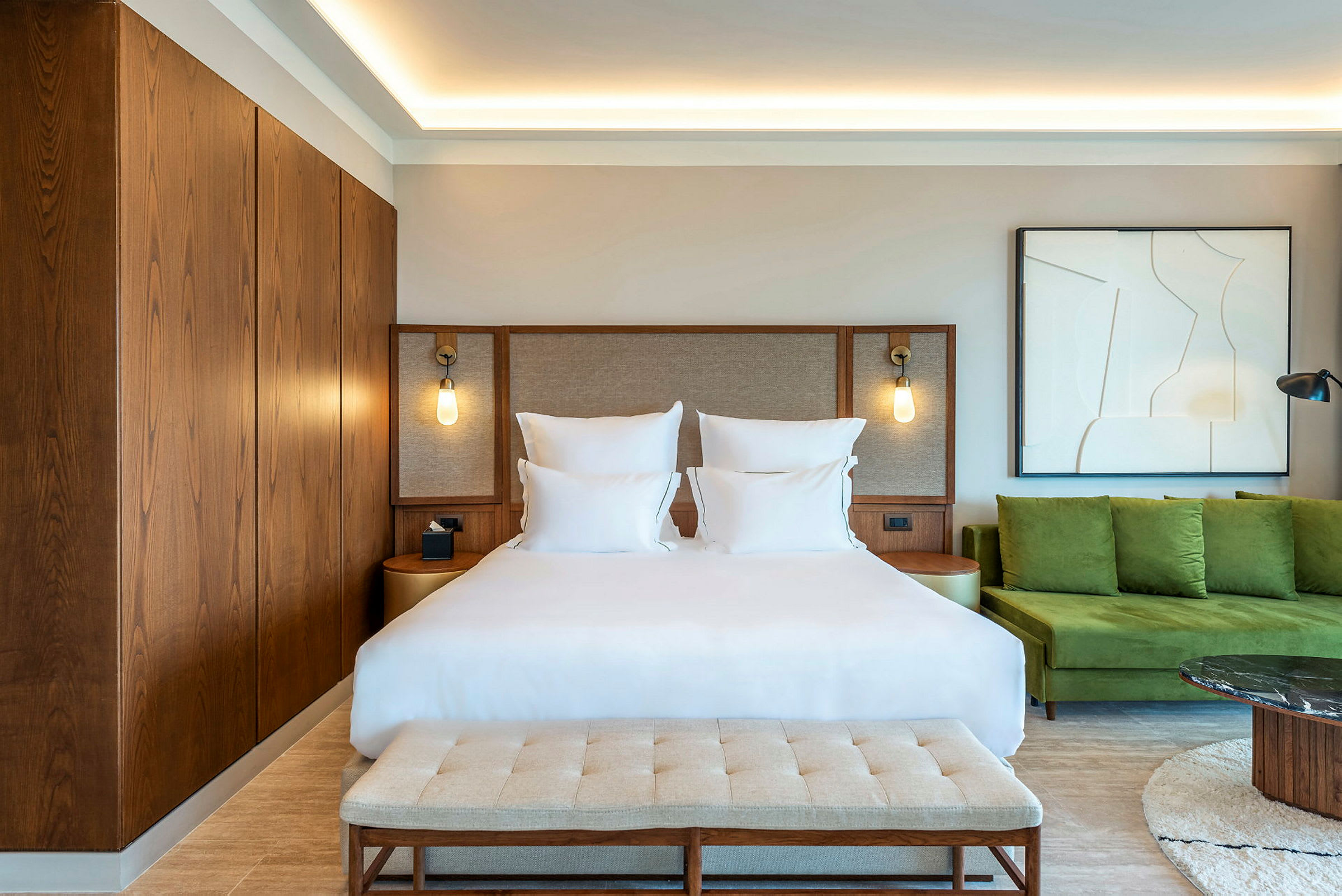 Hotelværelse med en dobbeltseng, moderne indretning og grønne siddepladser. (AI-genereret tekst)
