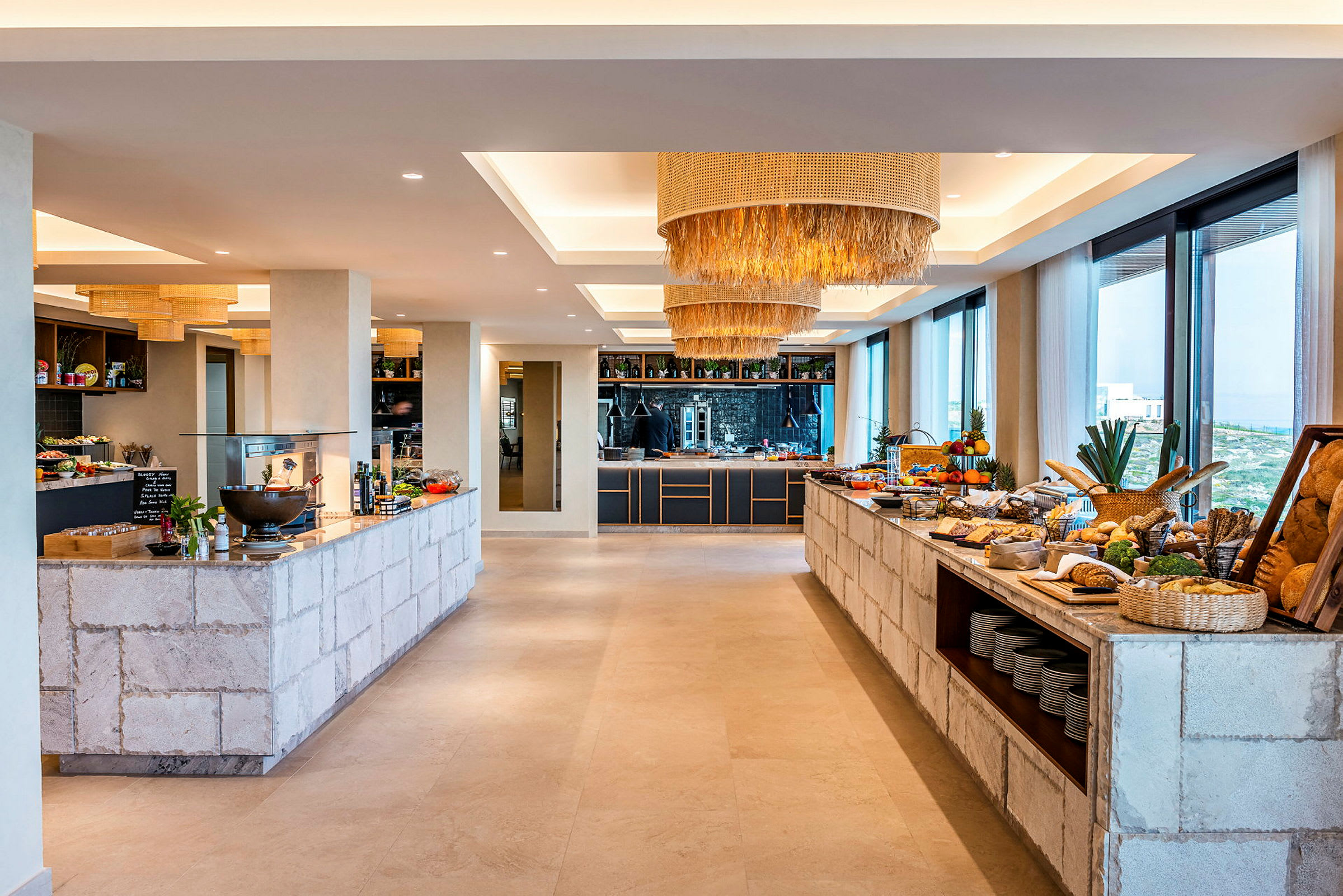 Interiør af en buffet med mad og drikke anrettet på stenmure, moderne lamper i loftet og store vinduer med udsigt. (AI-genereret tekst)
