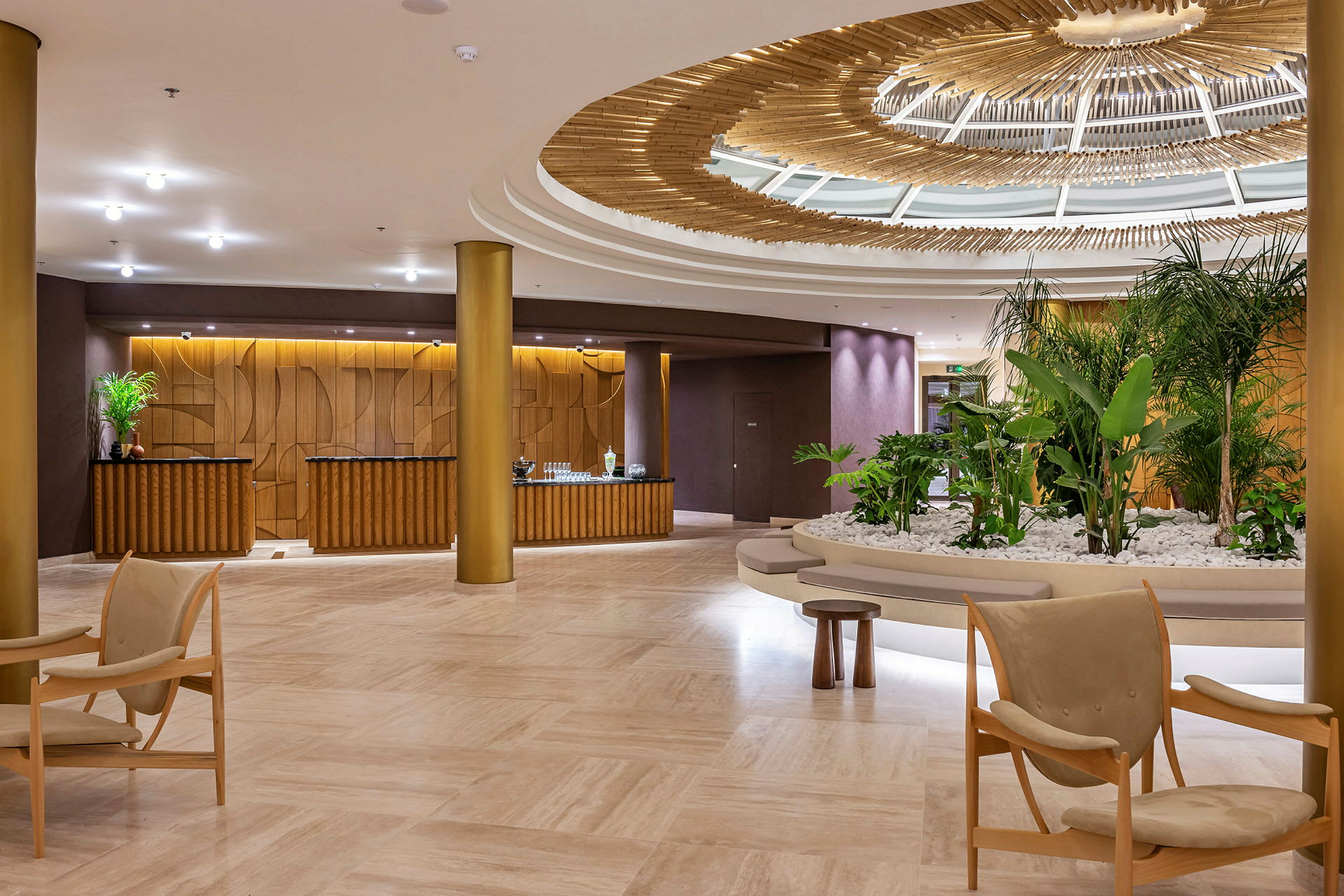 Et hotellobbyområde med elegant interiør, inklusive grønne planter, siddepladser og en dekorativ loftskonstruktion. (AI-genereret tekst)