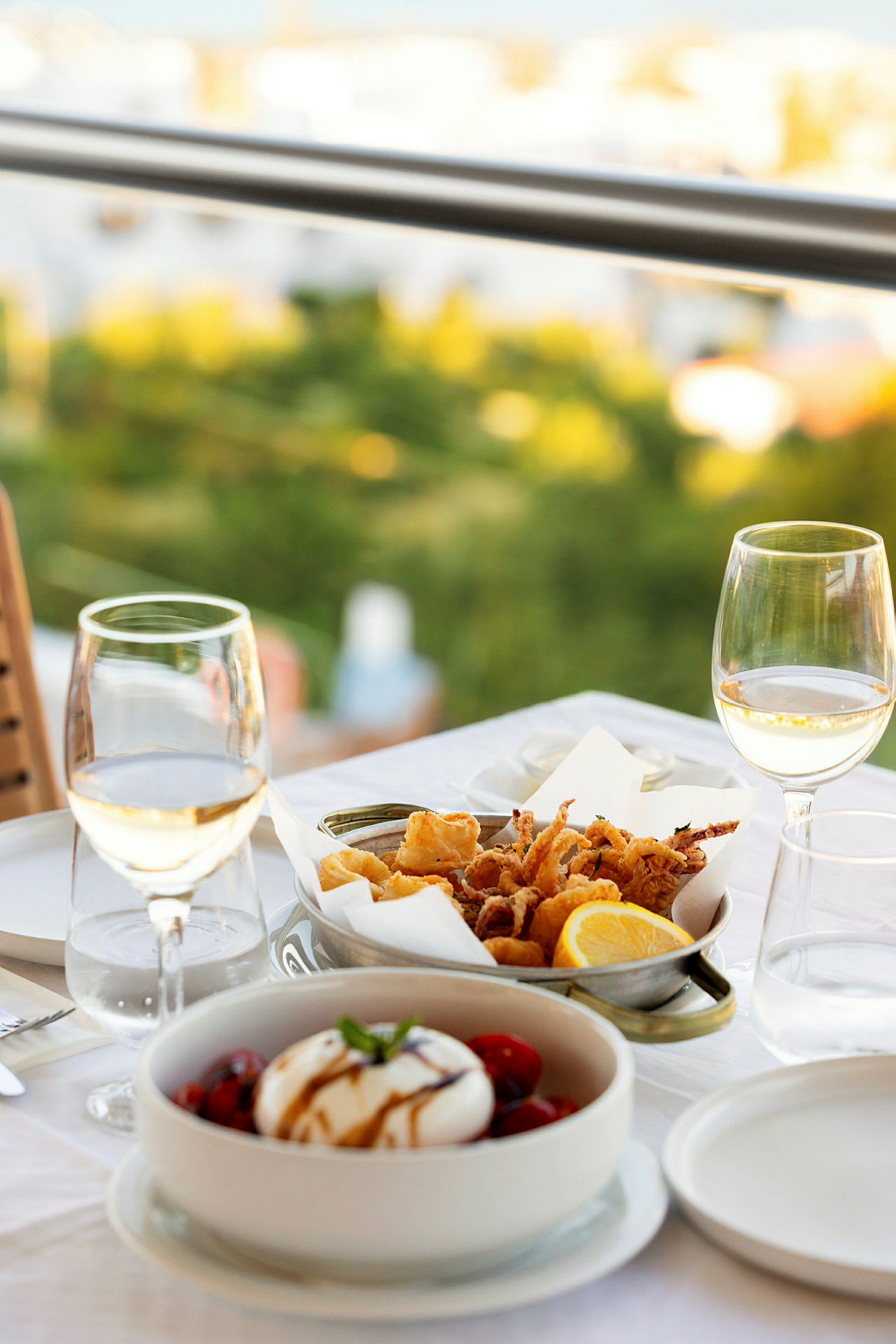 Et dækket bord med vin, salat og friturestegt fisk. (AI-genereret tekst)