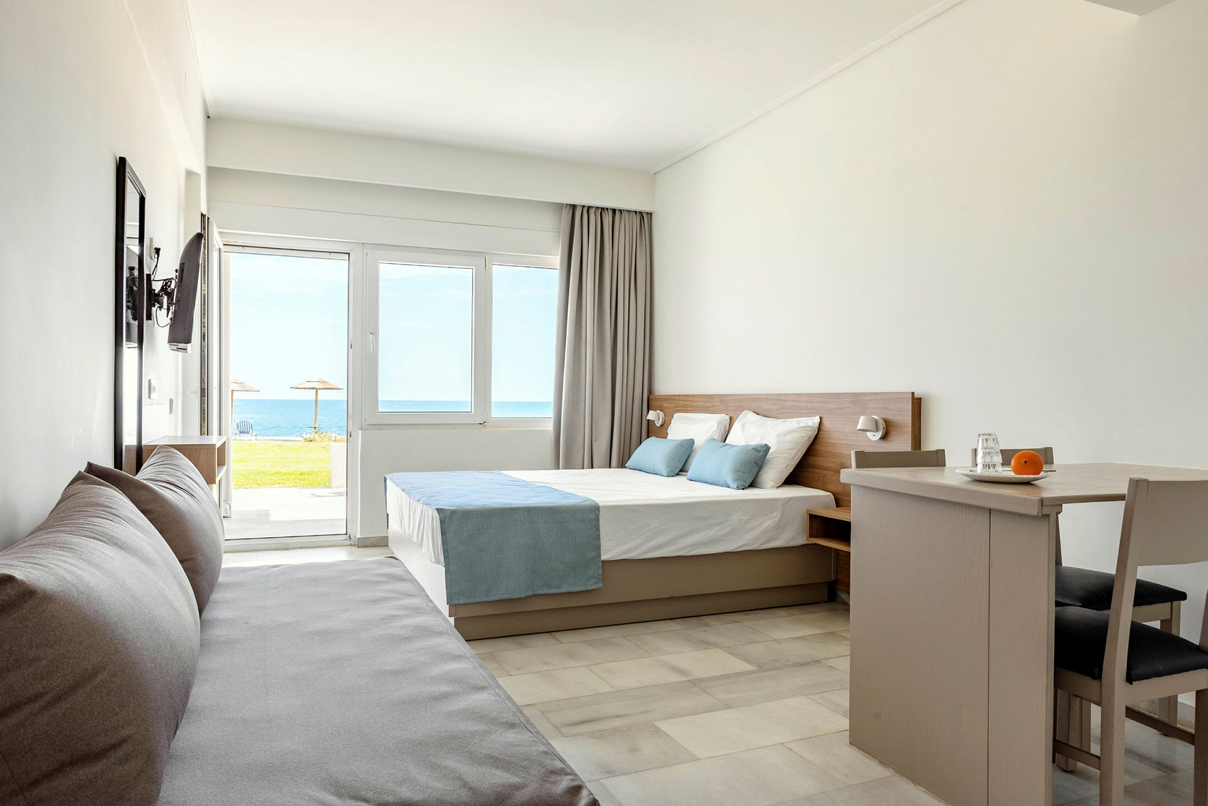 Moderne hotelværelse med seng, sofa og spisebord, havudsigt uden for vinduet. (AI-genereret tekst)